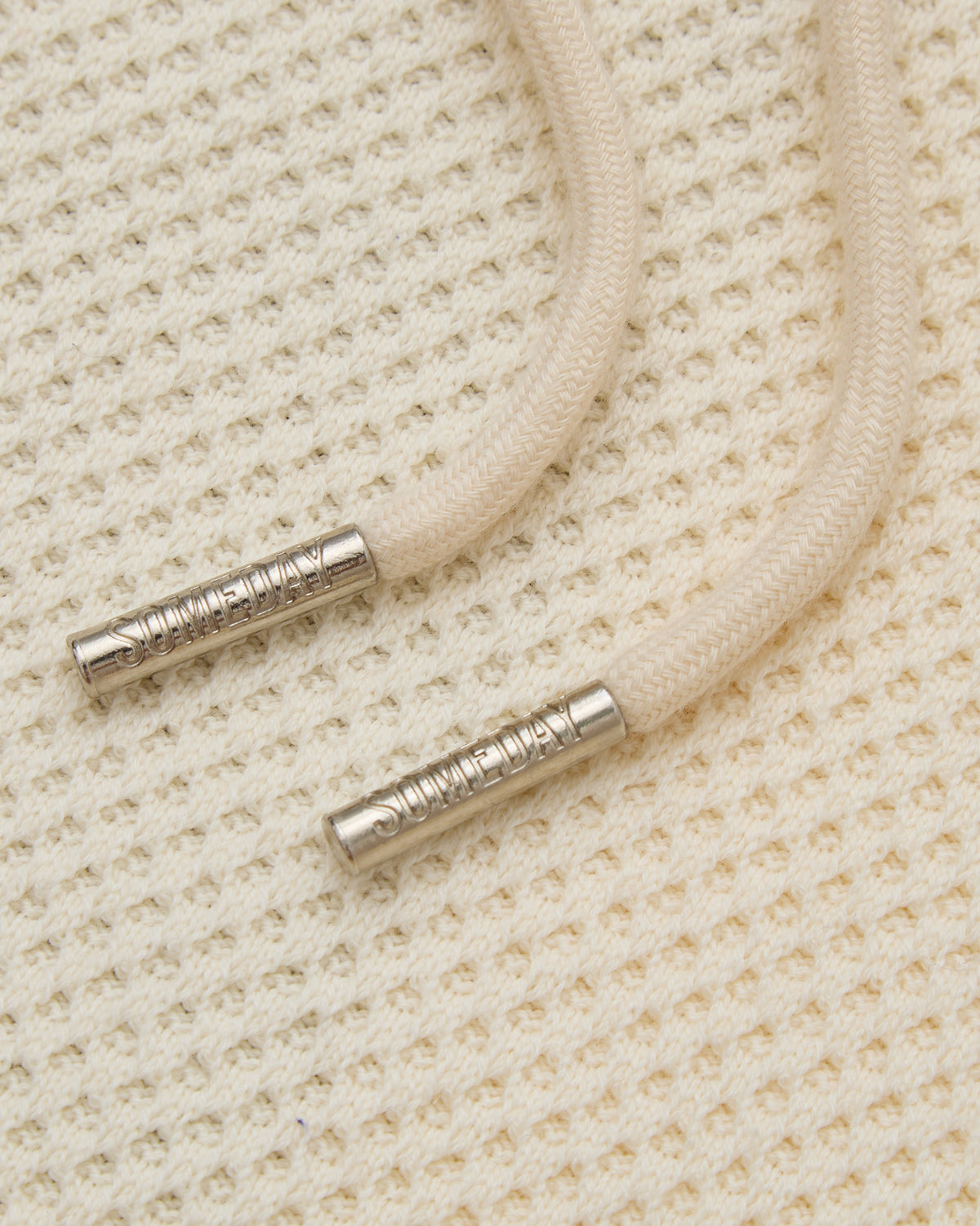 Close-up of beige cord with metal ends on a textured beige background