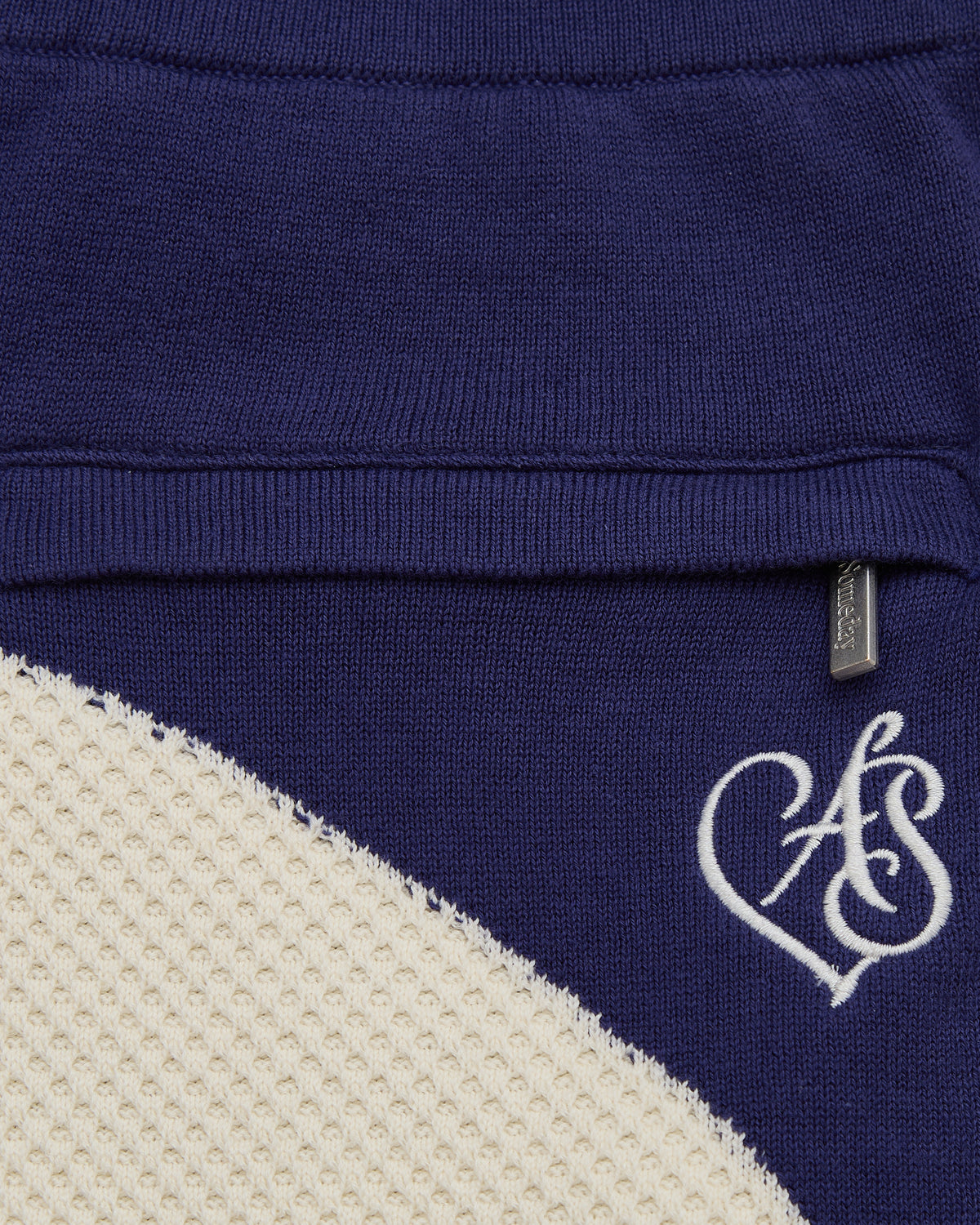 Close-up of a blue garment with a white logo on a beige background