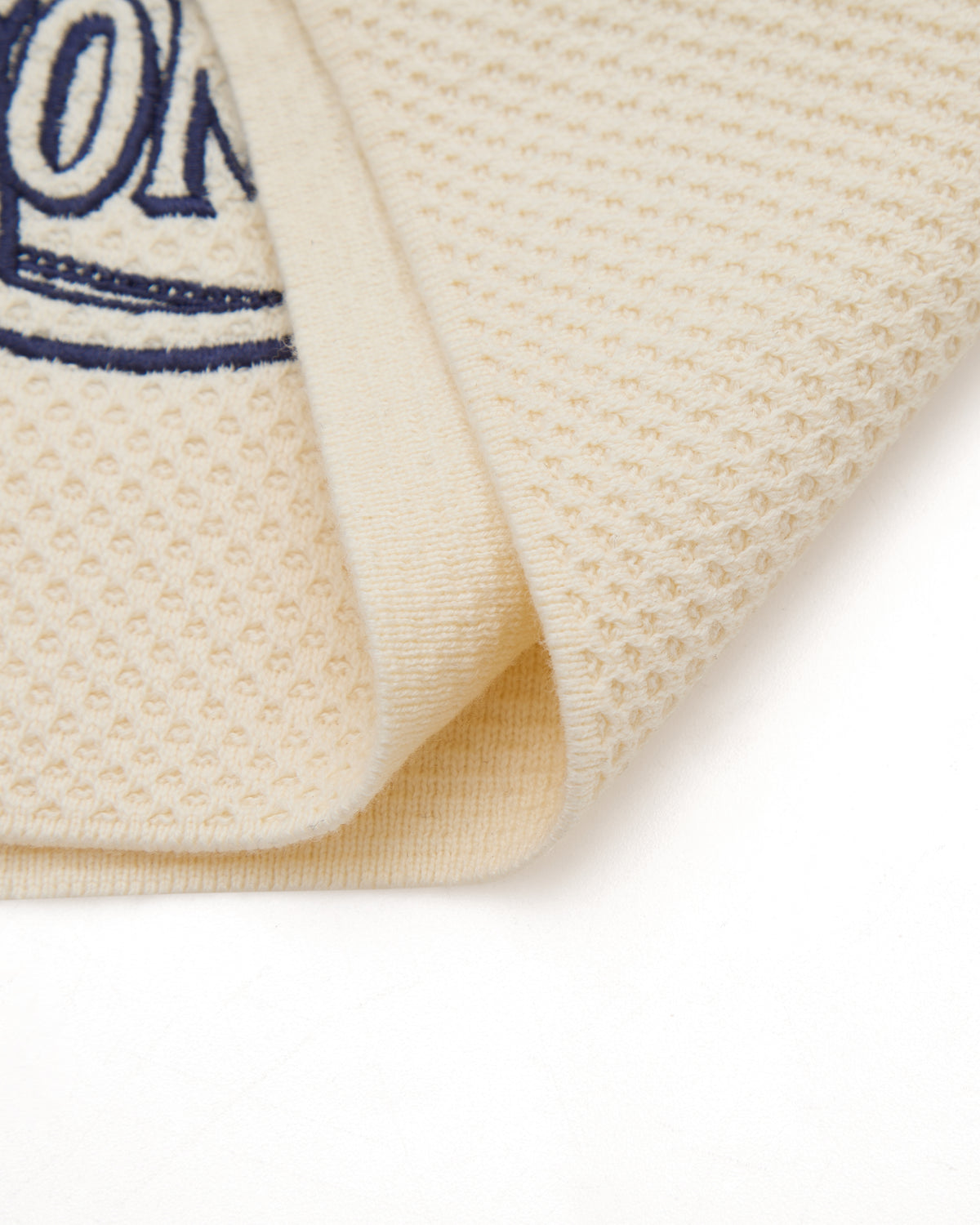 Close-up of a textured beige fabric with a blue logo on a white background