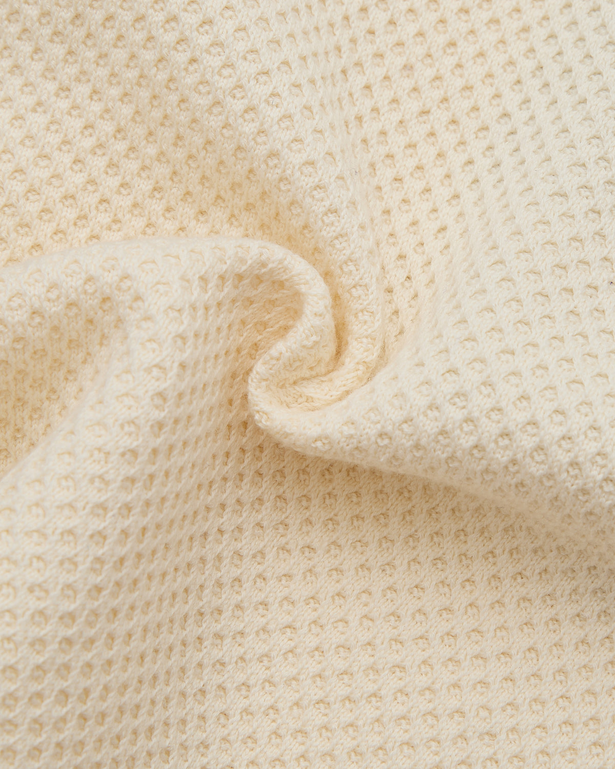 Close-up of beige textured fabric with a slight waffle pattern.