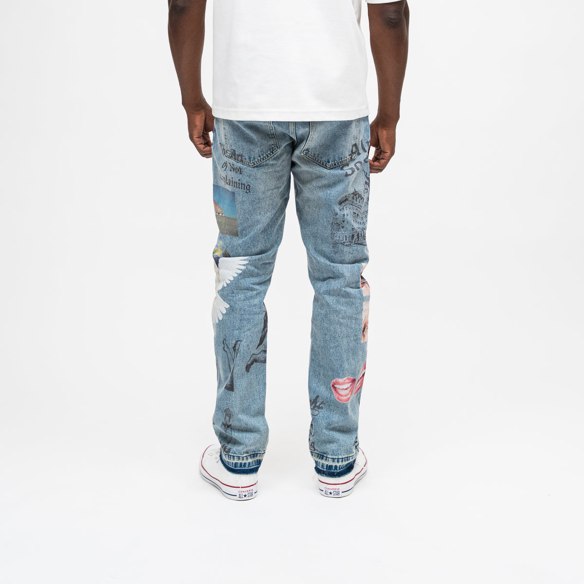 ALMOST SOMEDAY Gallery Denim Pant in Blue Wash, back view with Art of Not Explaining text, angel wings, lips, and architectural illustration