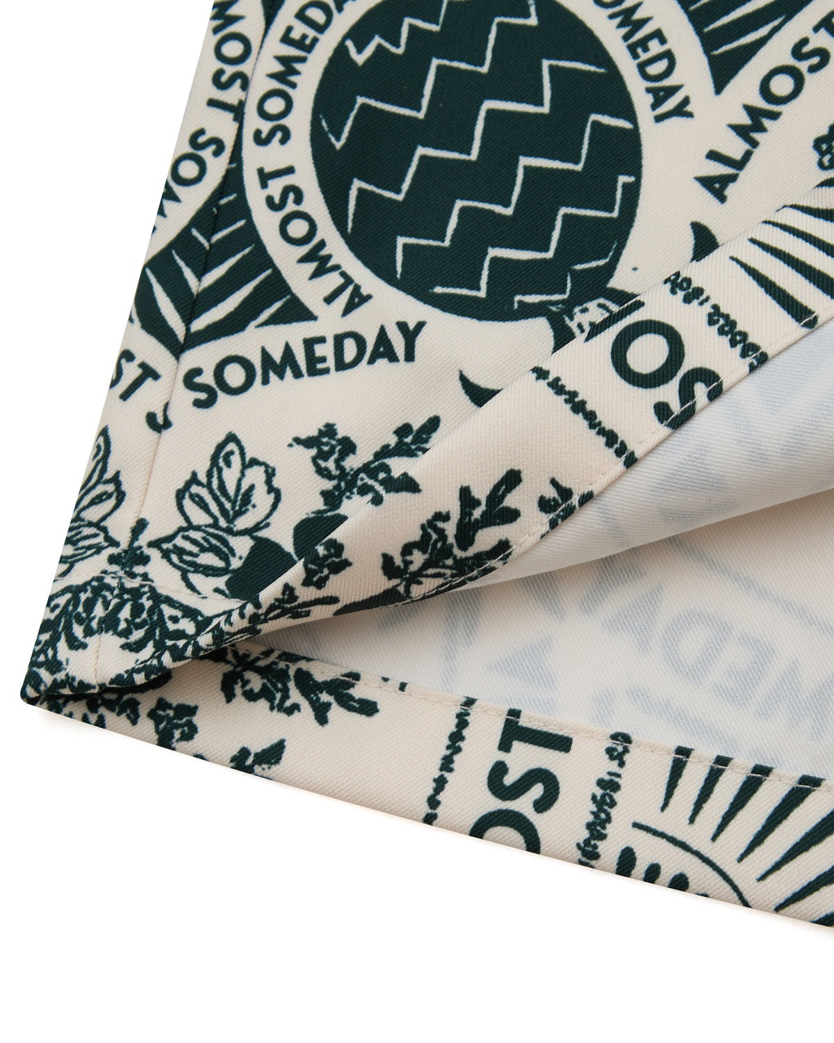 Folded fabric with 'ALMOST SOMEDAY' text and patterns on a white background