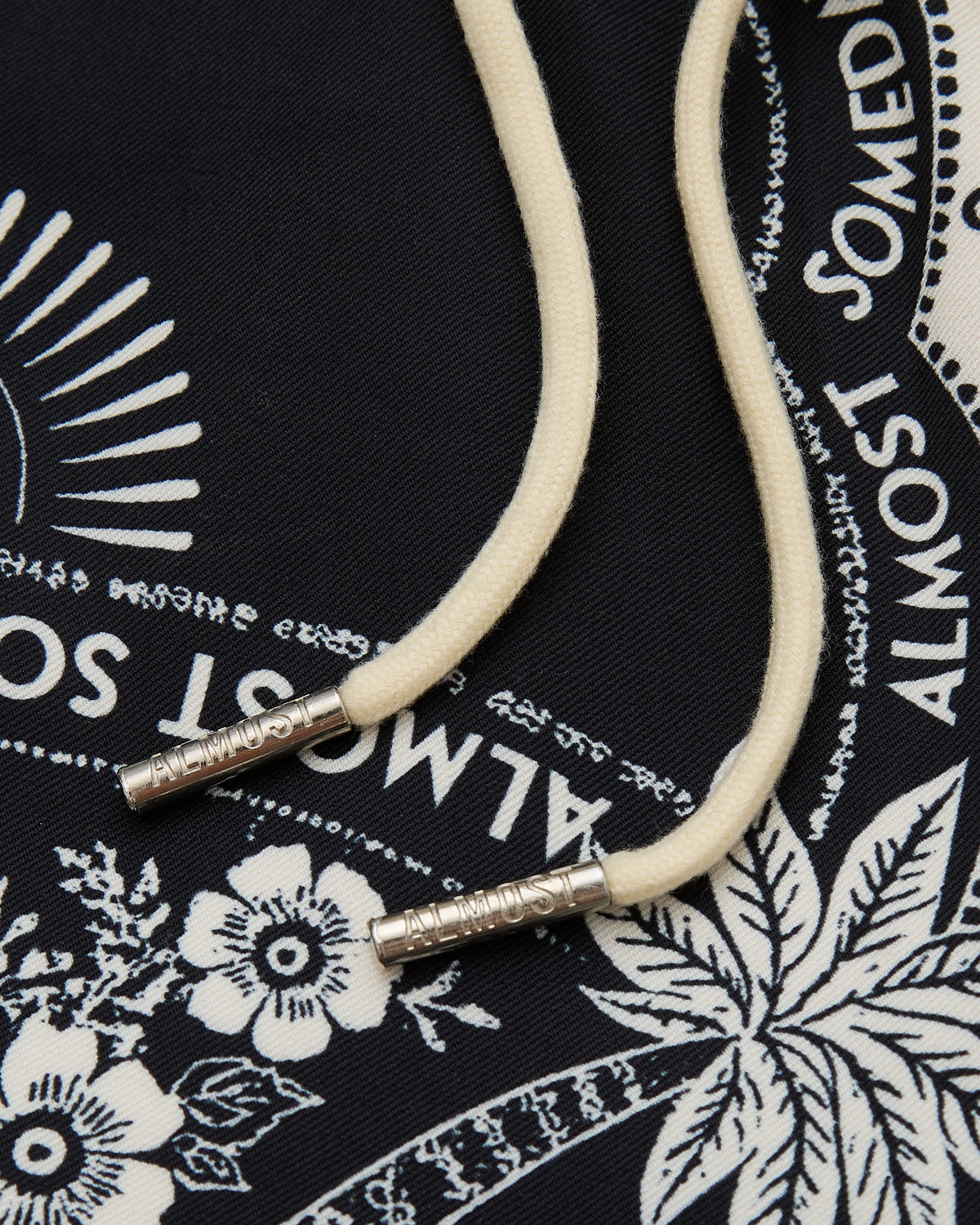 White cord with silver ends on a black bandana with white patterns