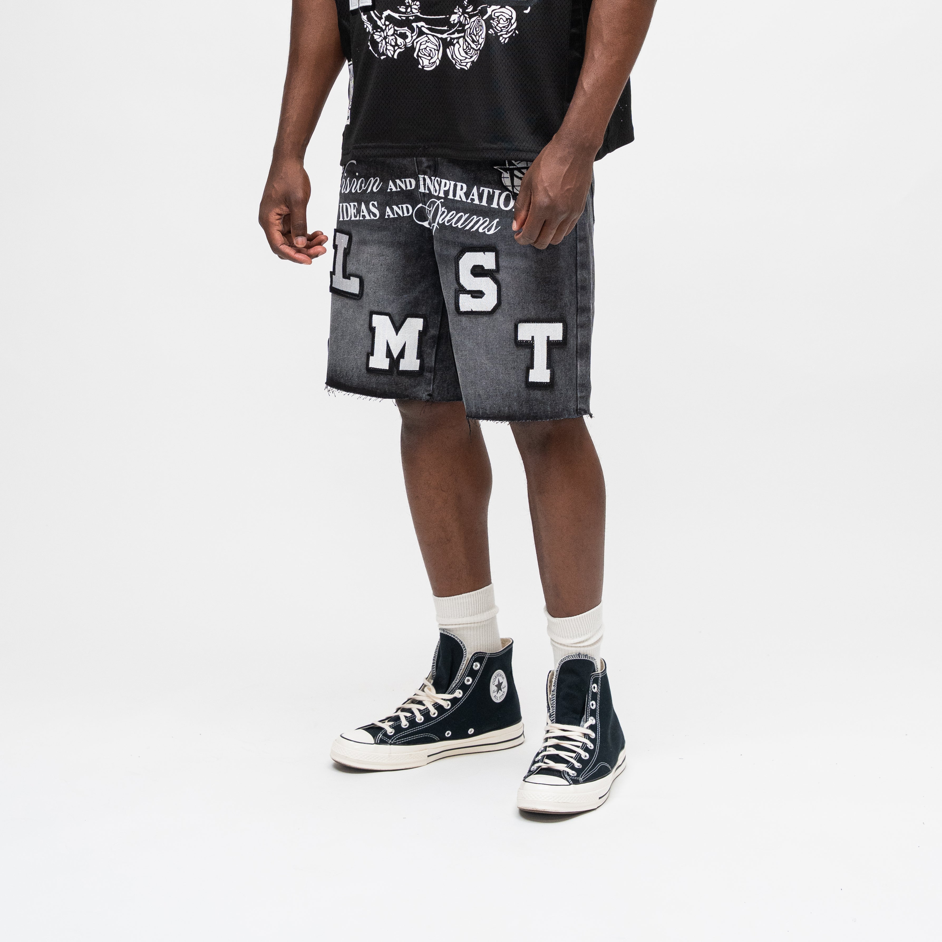 ALMOST SOMEDAY Letterman Denim Jort in Black, angled front view showing block letter appliqué detail, basketball star, and raw frayed hem