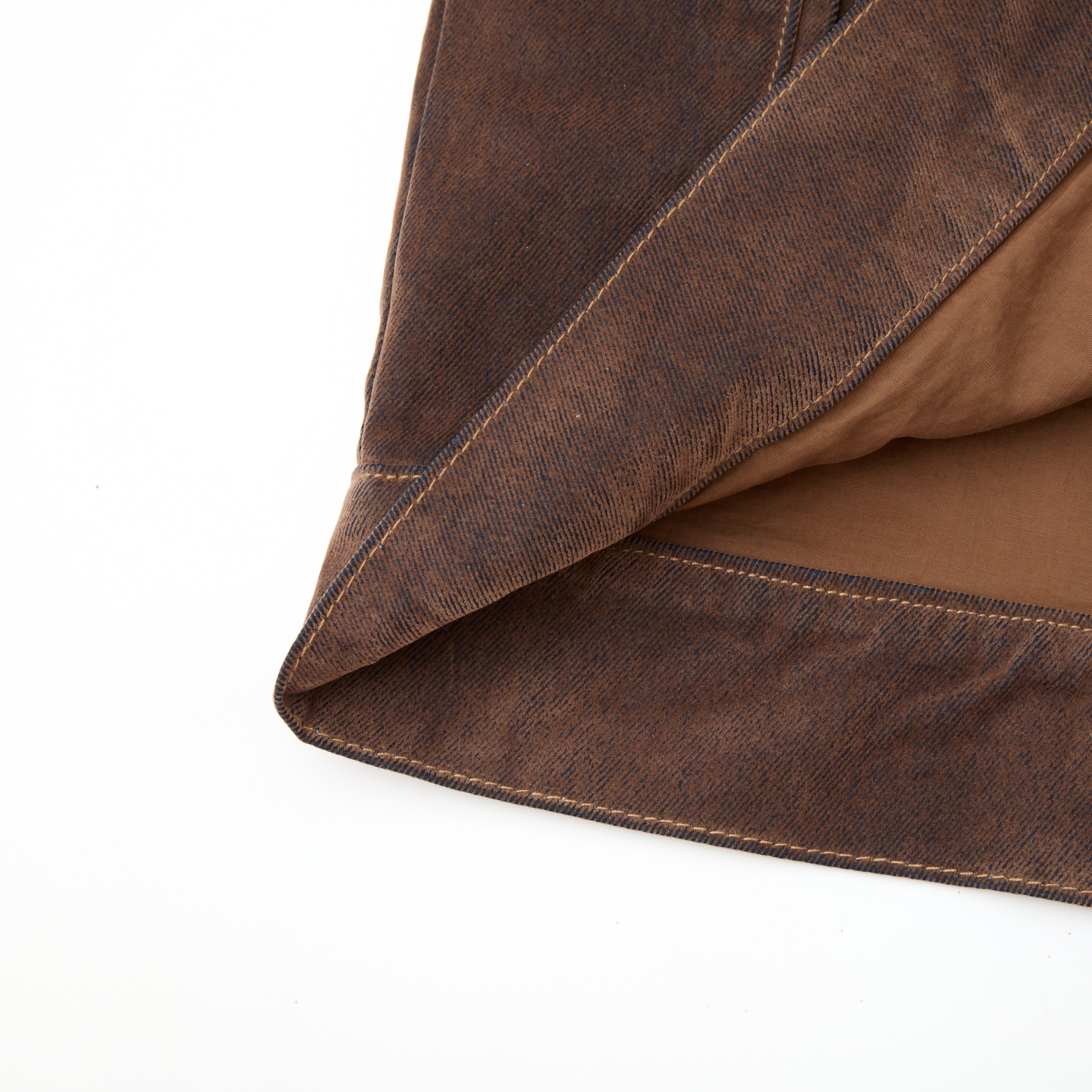 Close-up of brown leather fabric with visible stitching on a white background