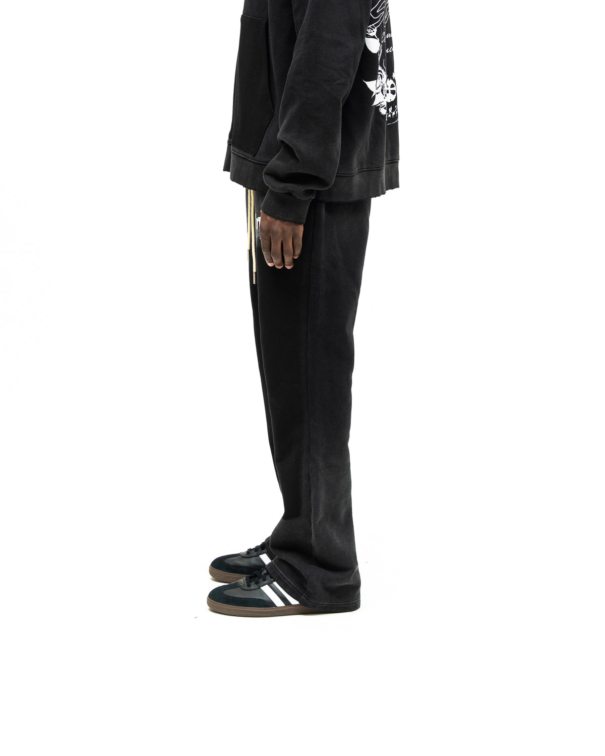 Enemies Flare Bottoms – Black – Side view on model styled with a black zip hoodie, showing leg silhouette and flared hem