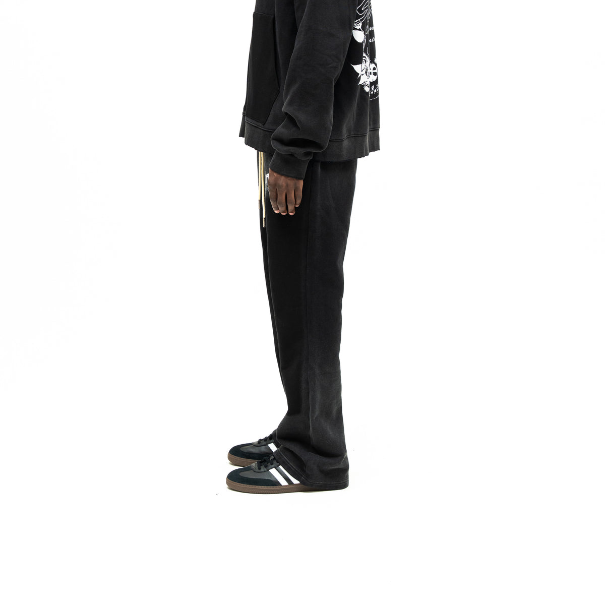 Enemies Flare Bottoms – Black – Side view on model styled with a black zip hoodie, showing leg silhouette and flared hem