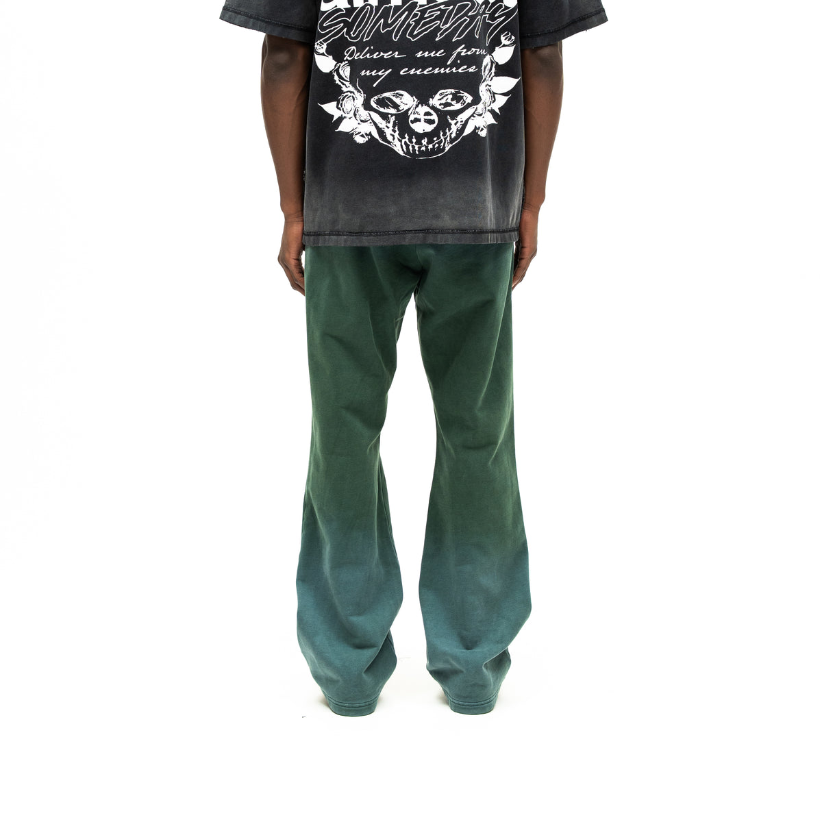 Enemies Flare Bottoms – Green – Back view on model styled with a black graphic tee, showing flared legs and faded green finish