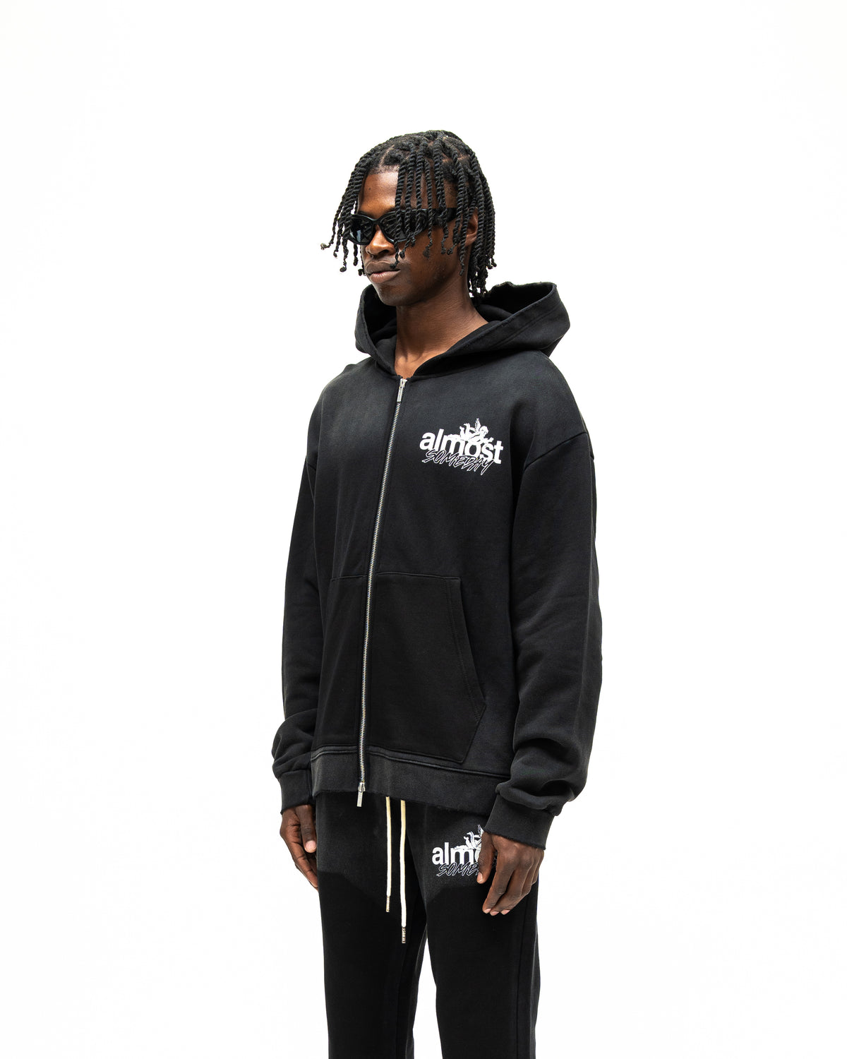 Enemies Zip Hoodie – Black – Three-quarter front view on model showing chest logo, dropped shoulders, and relaxed fit