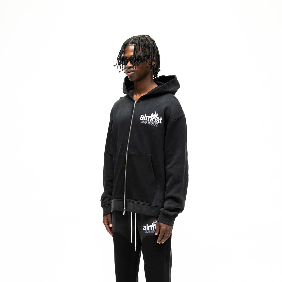 Enemies Zip Hoodie – Black – Three-quarter front view on model showing chest logo, dropped shoulders, and relaxed fit