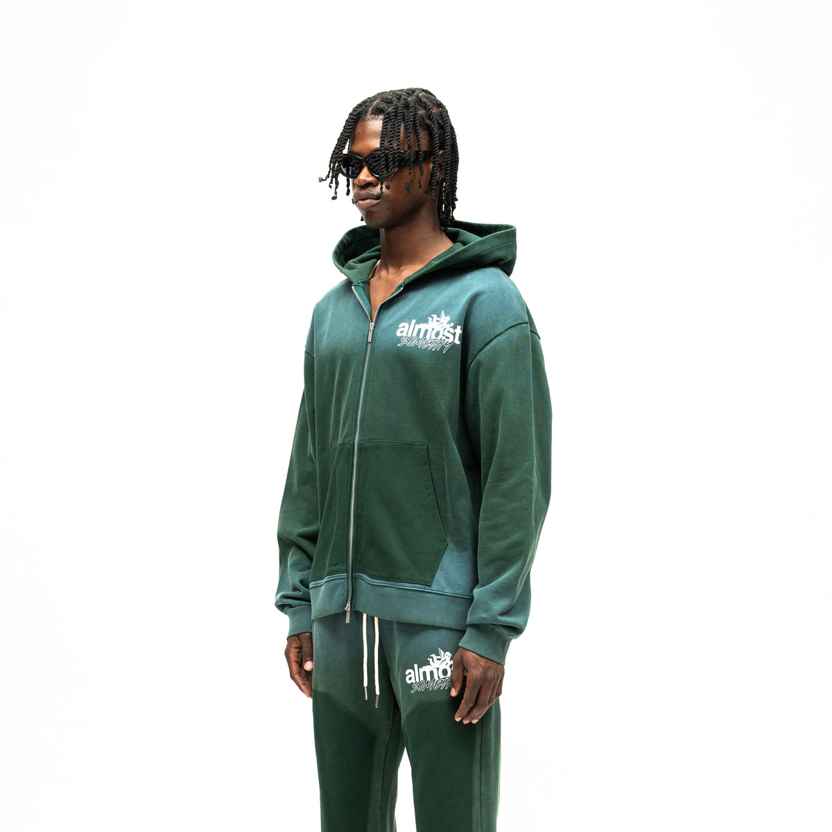 Enemies Zip Hoodie – Green – Three-quarter front view on model showing chest logo, dropped shoulders, and contrasting front pockets