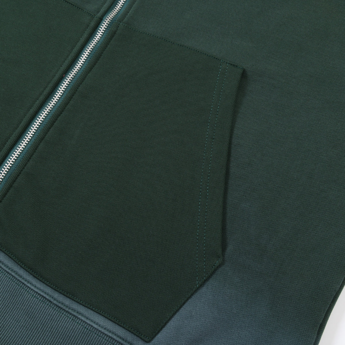 Enemies Zip Hoodie – Green – Close-up of dark green front pocket opening, stitching, and silver-tone zipper teeth