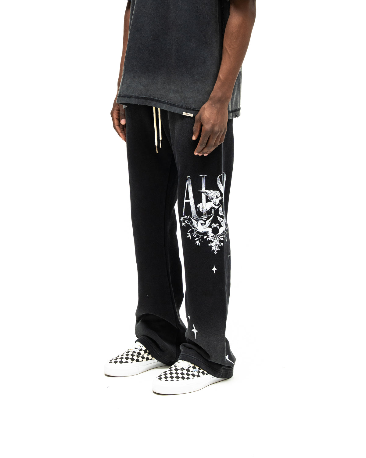 League Flare Sweatpants – Black – Three-quarter front view on model styled with a tee, showing white cherub and star leg graphics