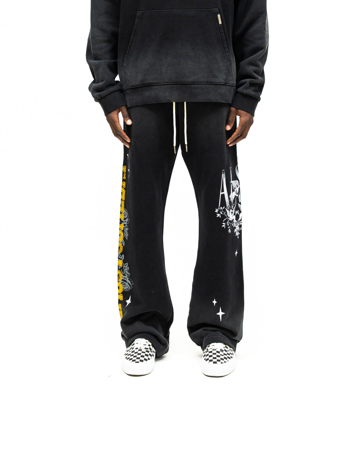 League Flare Sweatpants – Black – Front view on model styled with a hoodie, showing white drawstrings and contrasting leg graphics