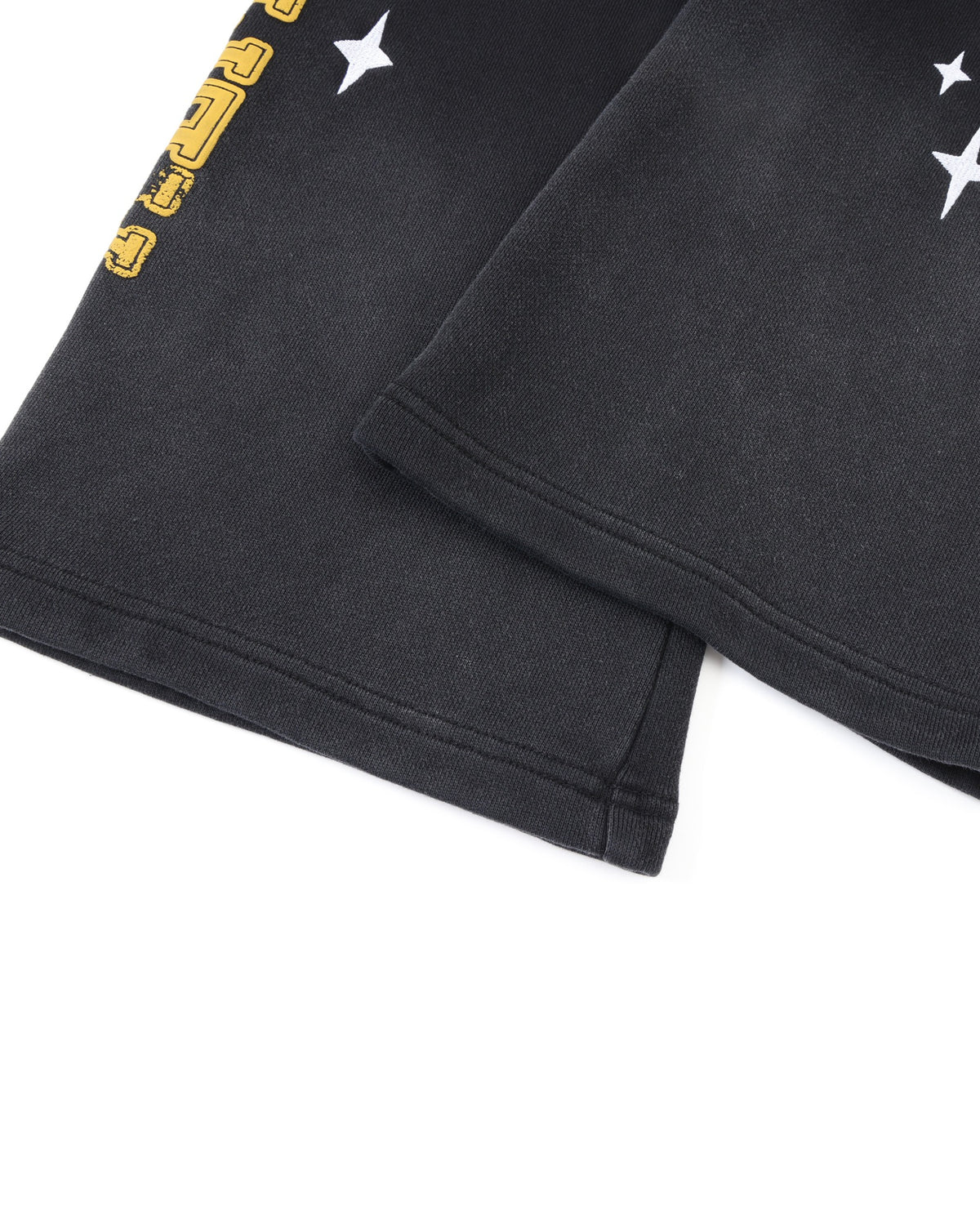 League Flare Sweatpants – Black – Close-up of stitched flared hems with white star graphics