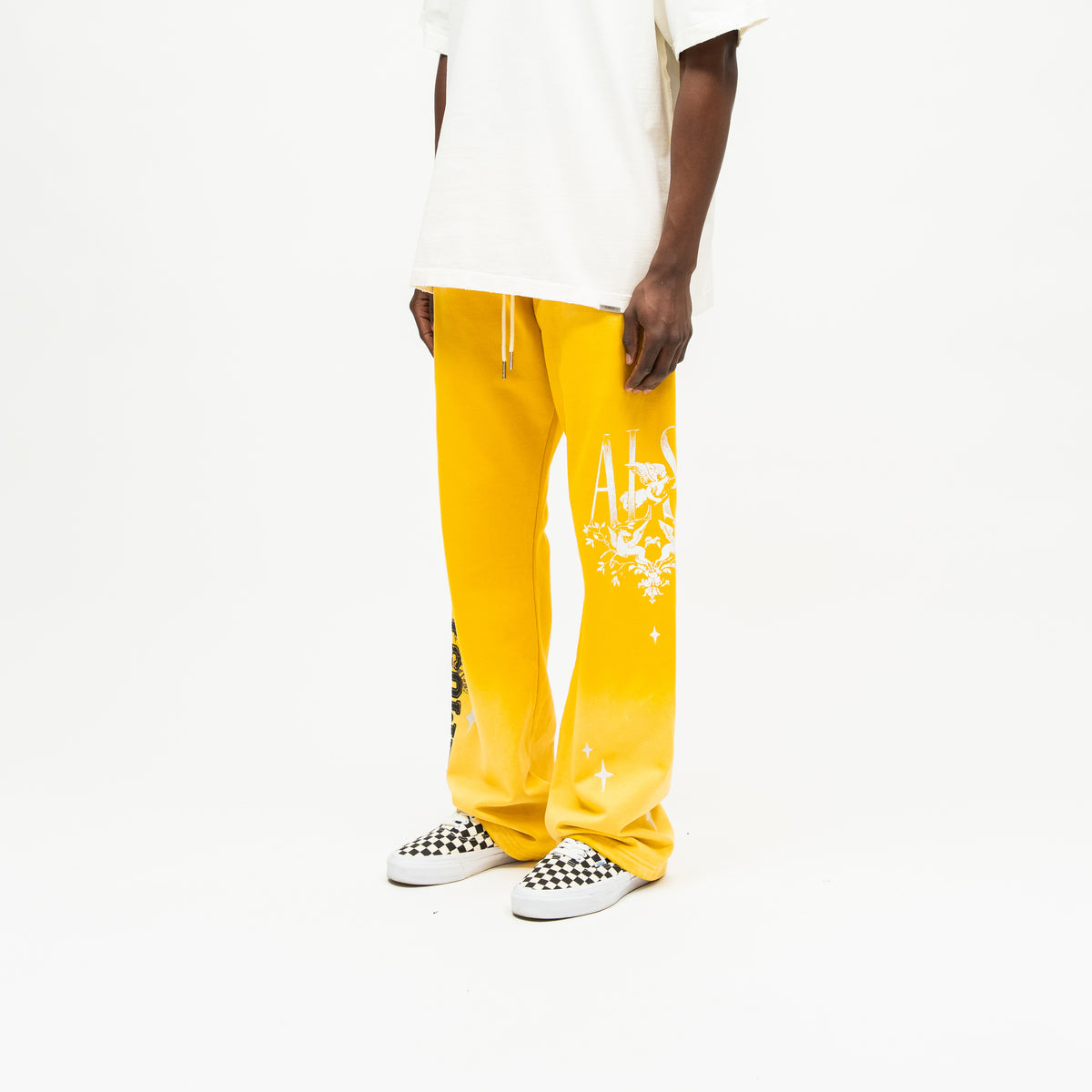 League Flare Sweatpants – Yellow – Three-quarter front view on model styled with a cream tee, showing flared sweatpants white cherub and star leg graphics