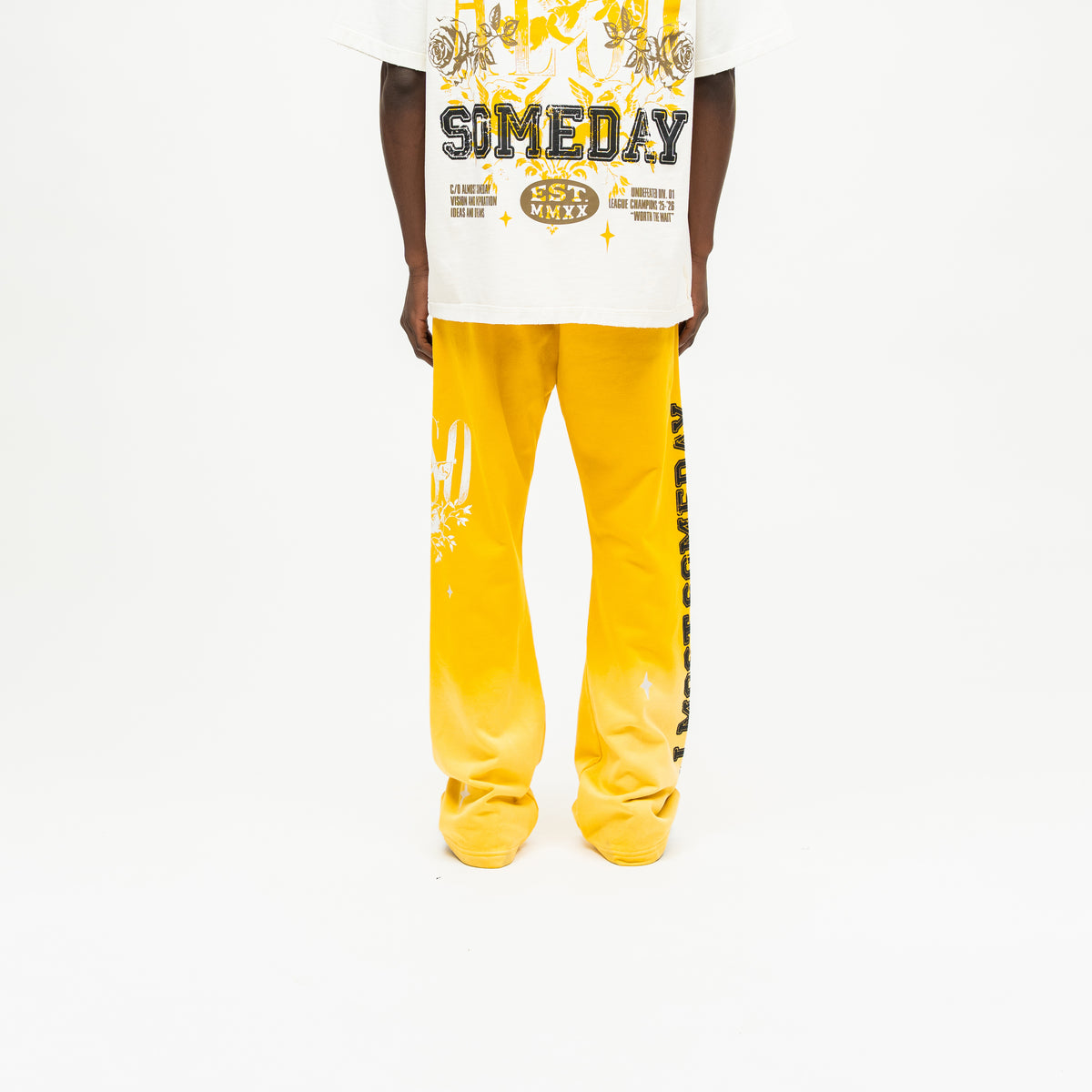 League Flare Sweatpants – Yellow – Back view on model styled with a cream tee, showing flared legs and black side lettering