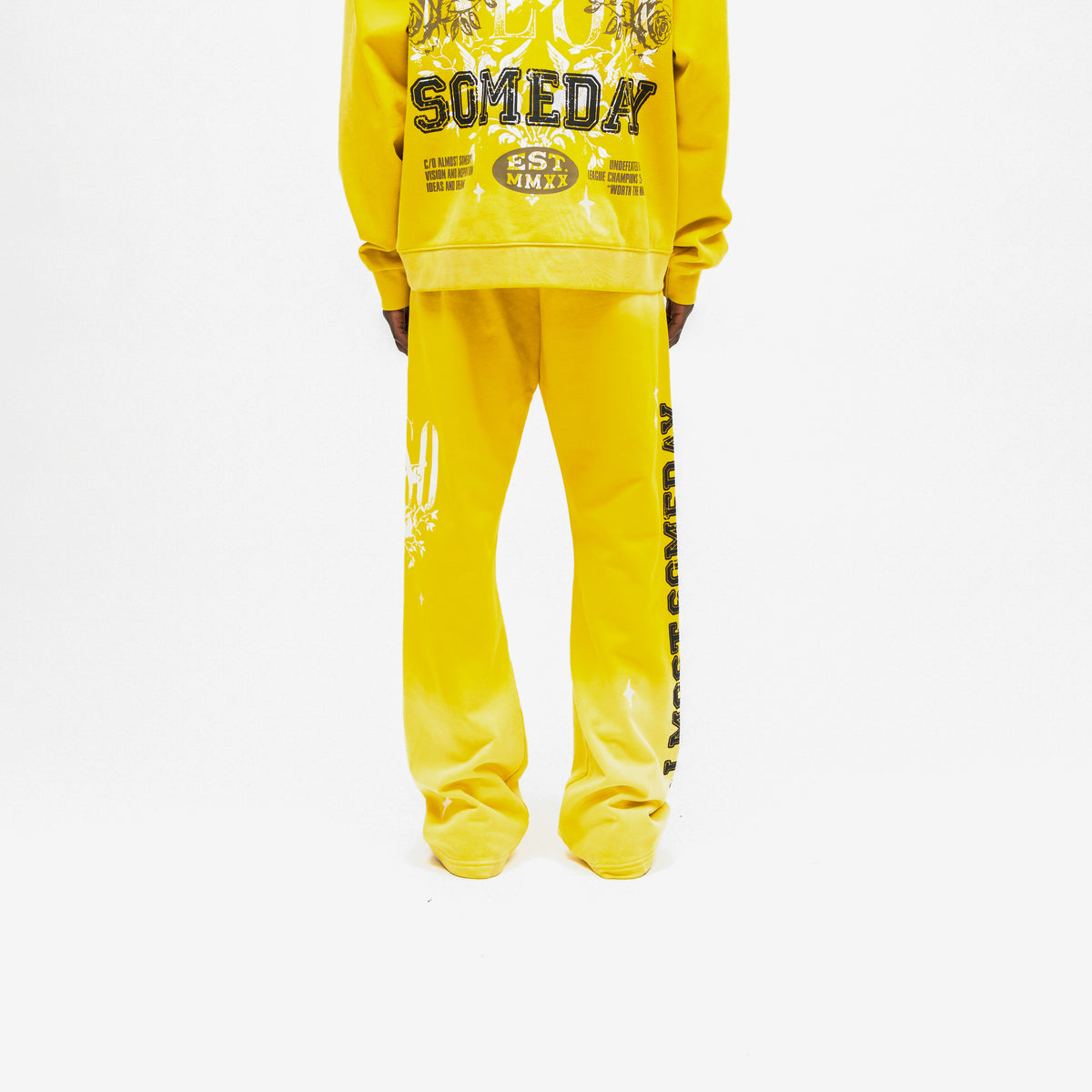 League Flare Sweatpants – Yellow – Back view on model styled with a matching hoodie, showing flared legs and black side lettering