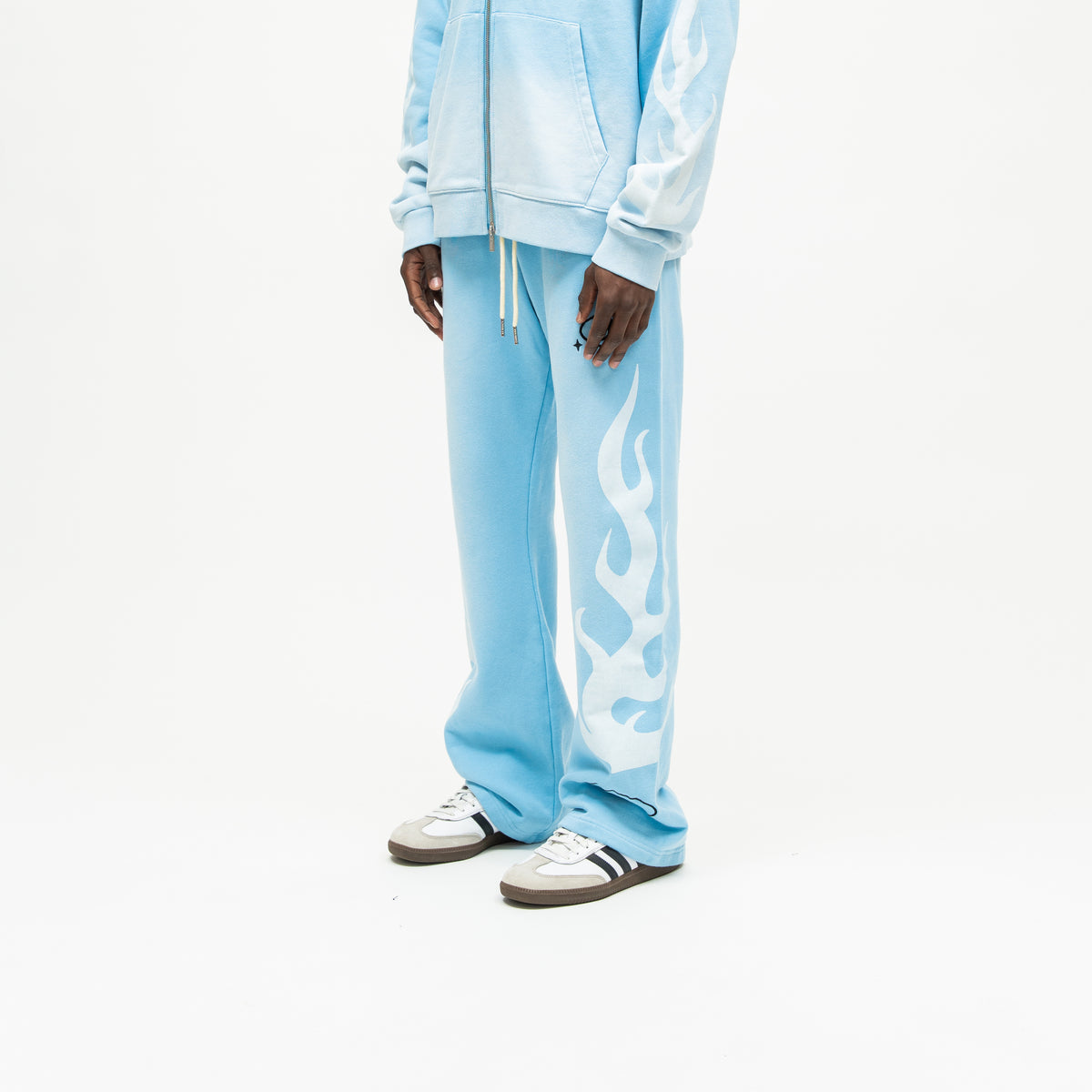 Members Flare Sweatpants – Light Blue – Three-quarter front view on model showing white flame graphic down outer leg and wide leg opening