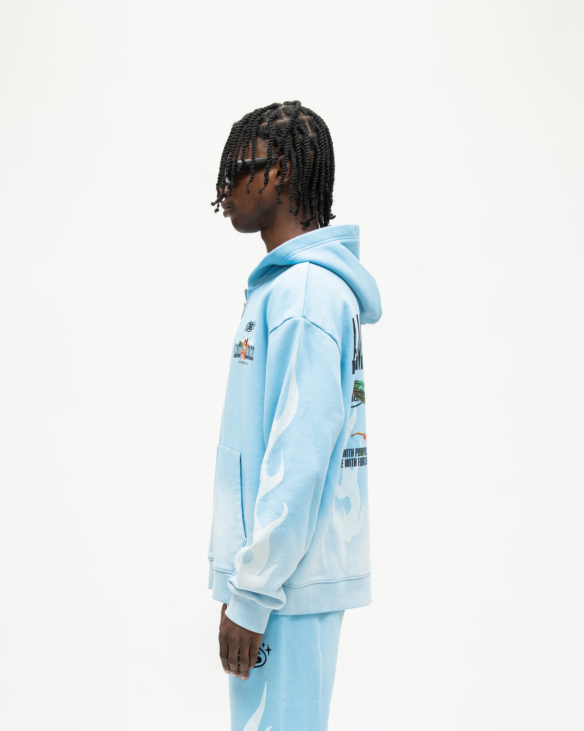 Members Zip Hoodie – Light Blue – Side view on model showing hood, white flame sleeve graphic, and ribbed cuff and hem