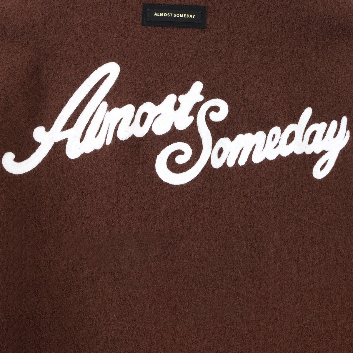 Saint Cropped Wool Jacket – Brown – Close-up of white back script and black brand patch