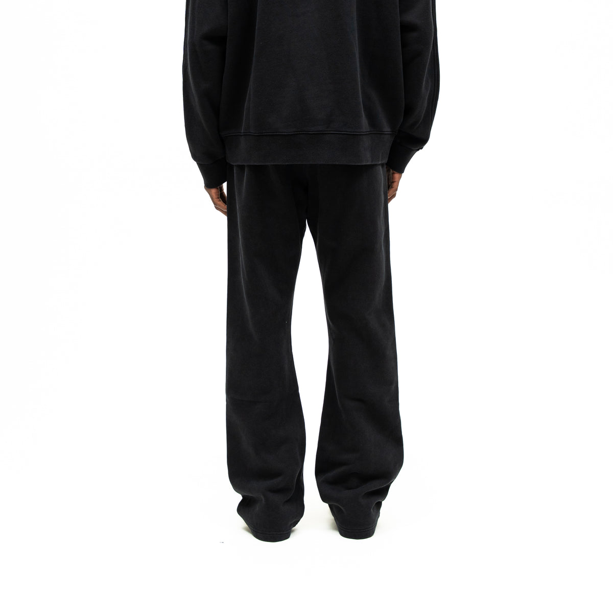 Smoke Flare Bottoms – Black – Back view on model styled with black crewneck, showing plain seat and wide hems
