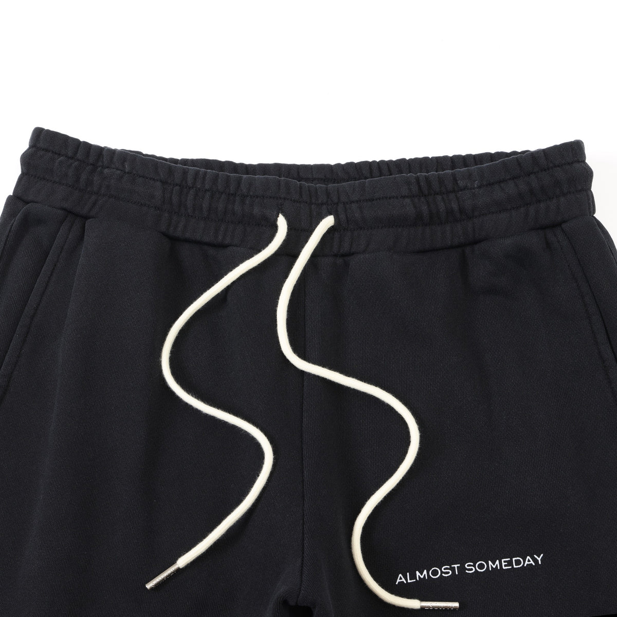 Smoke Flare Bottoms – Black – Close-up of elastic waistband, cream drawstrings, front pockets, and thigh lettering