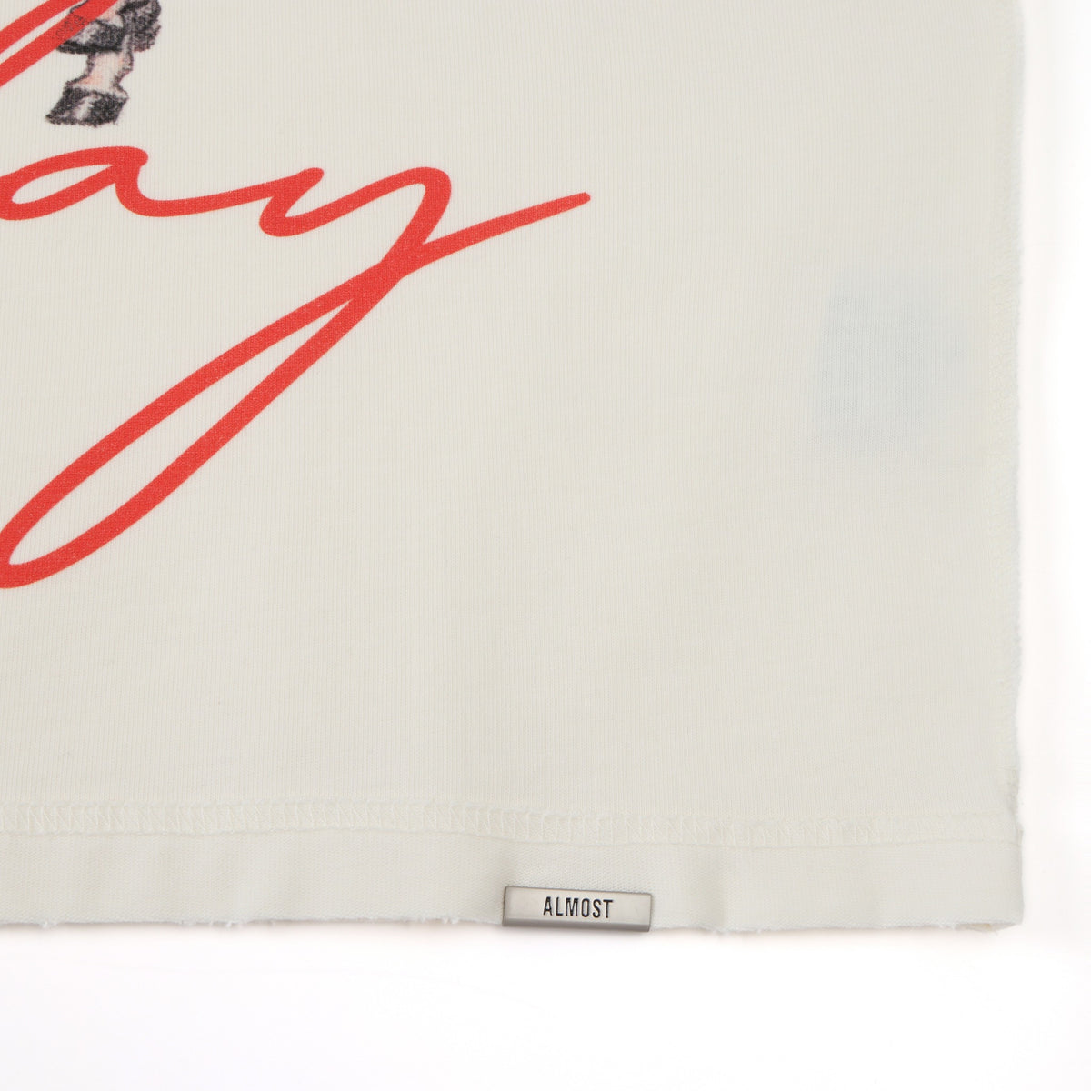 Smoke Tee – Cream – Close-up of lower hem with Almost label and red script detail