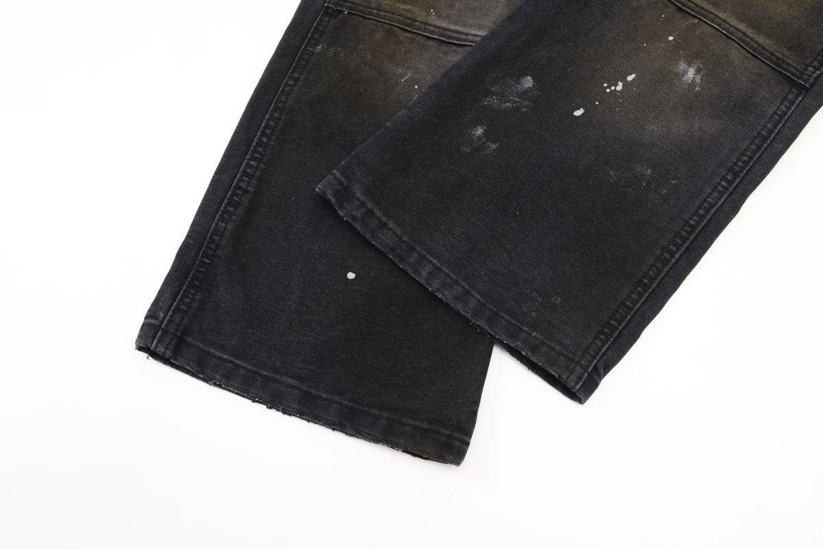 Spade Pants – Black – Close-up of overlapping leg hems showing faded finish, stitching, and paint splatters