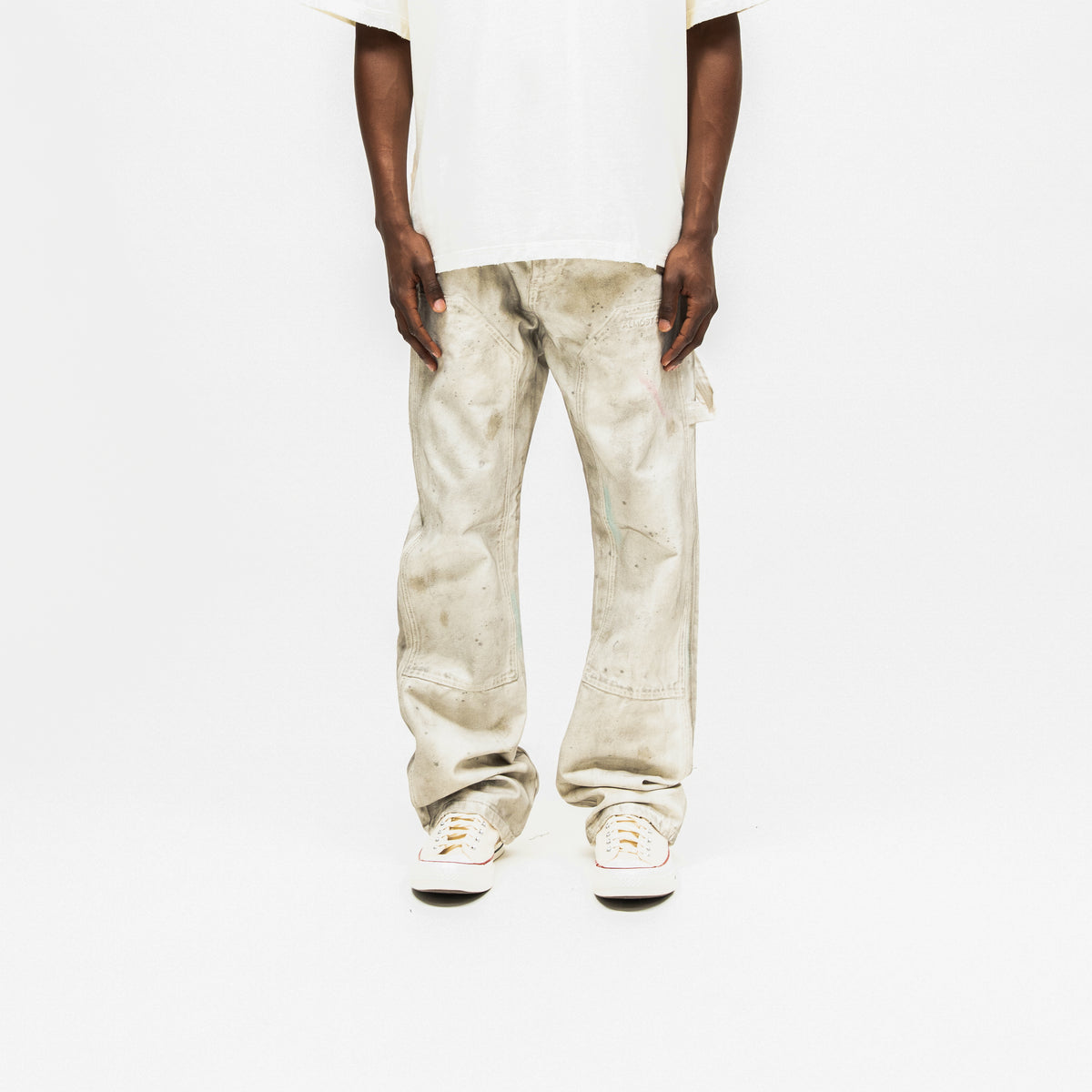 Spade Pants – Cream – Front view on model styled with white tee, showing mottled finish, stitched thigh panels, and wide hems