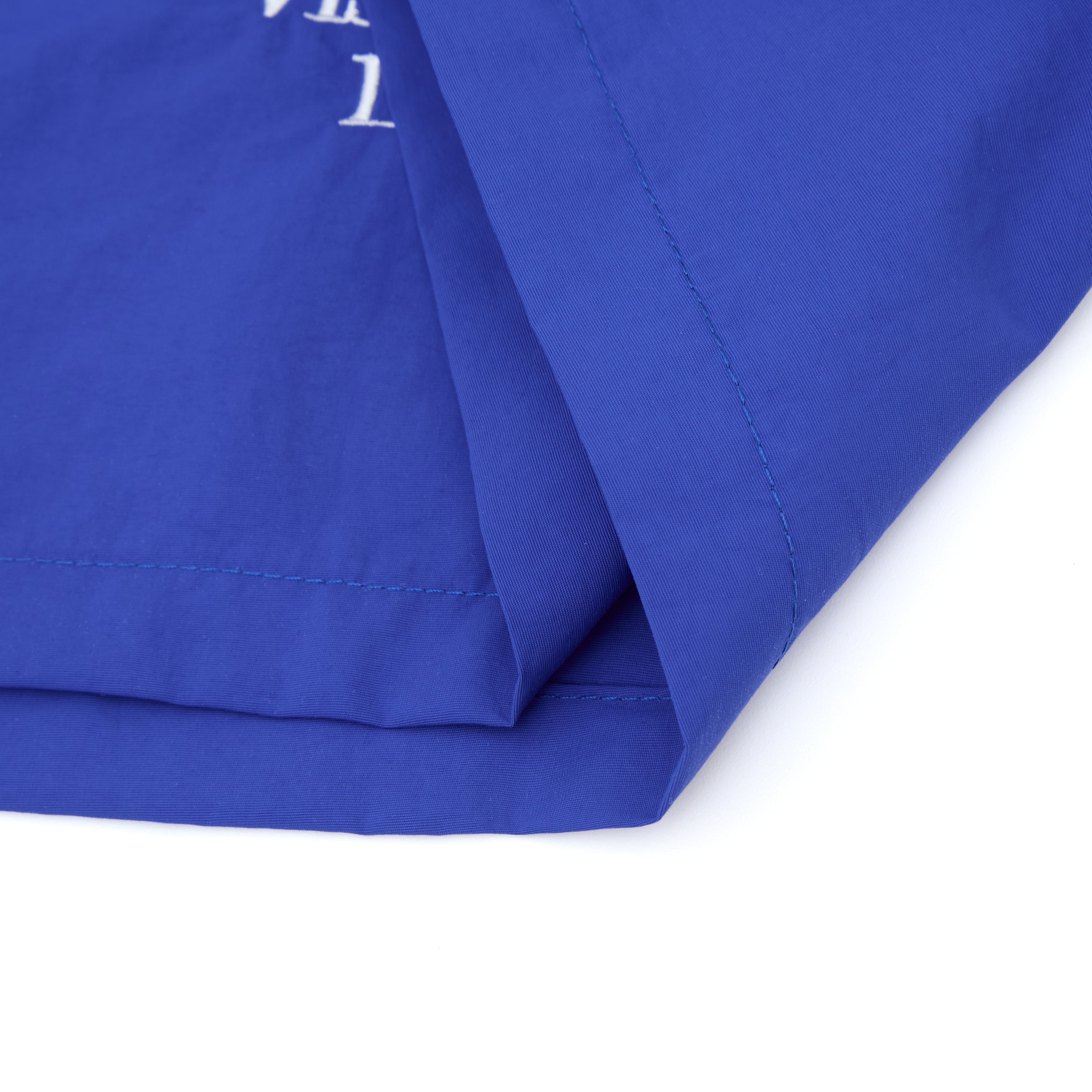 Close-up of blue fabric with a white logo on a white background