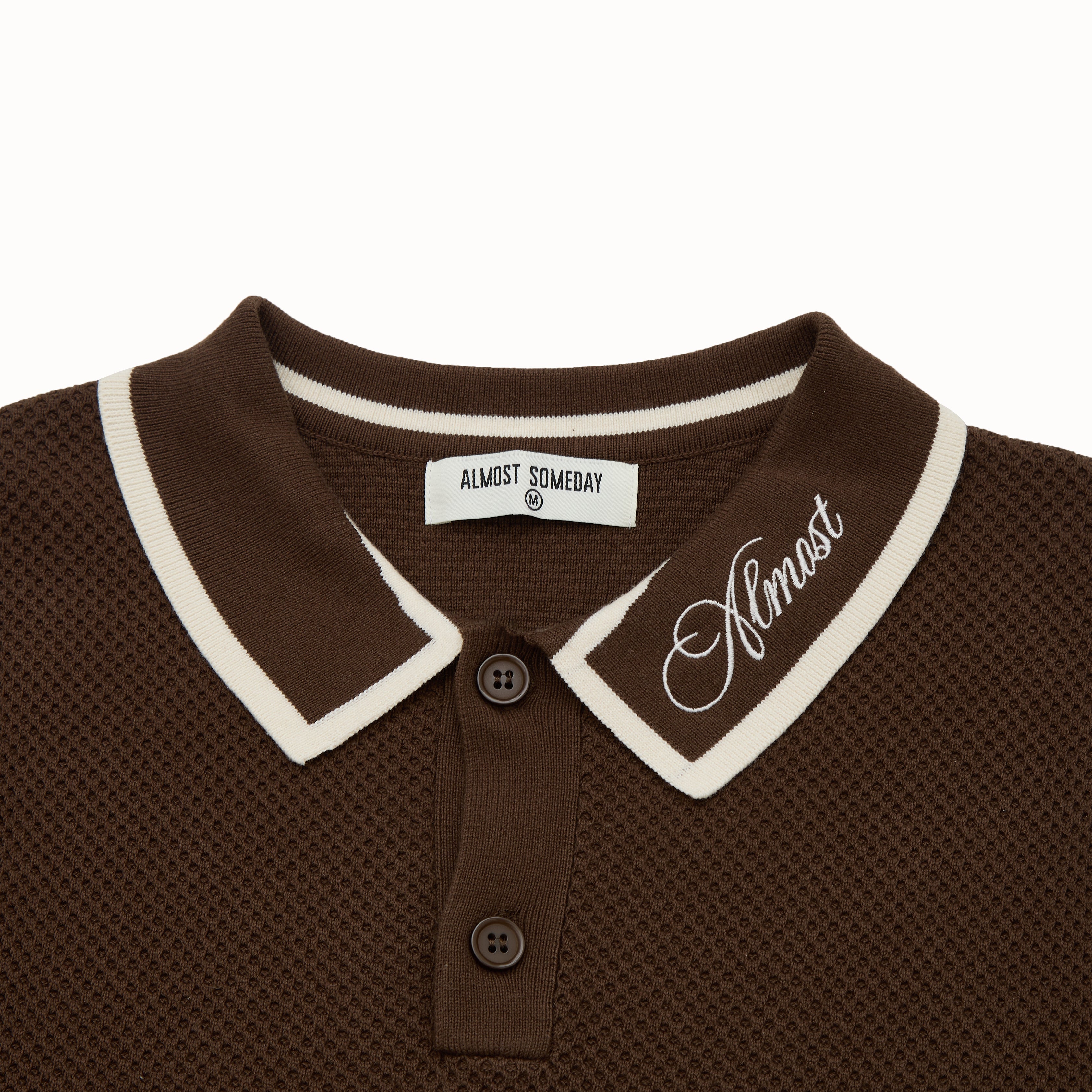 Brown polo shirt with white trim and 'Almost' branding on a white background