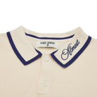 Close-up of a cream-colored polo shirt with navy trim and 'Almost' branding.