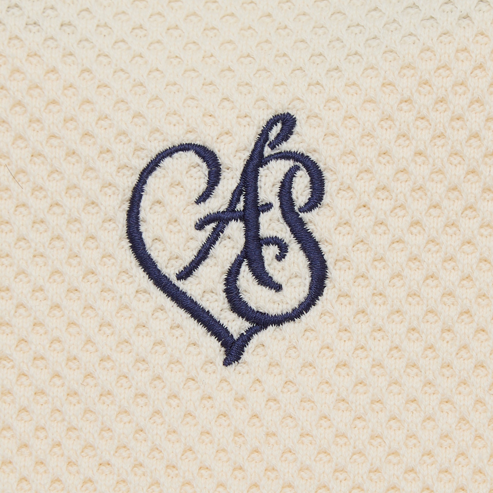 Navy blue embroidered monogram on beige textured fabric
