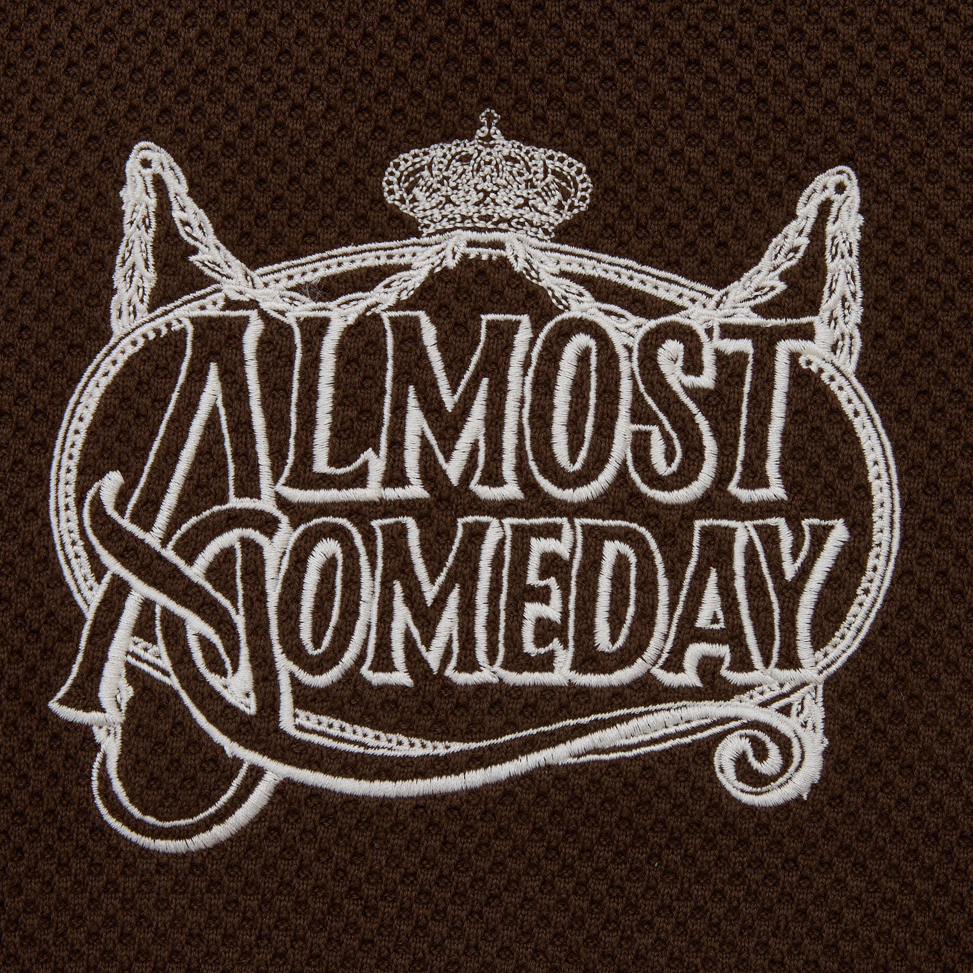 Embroidered patch with 'Almost Someday' text on a brown background