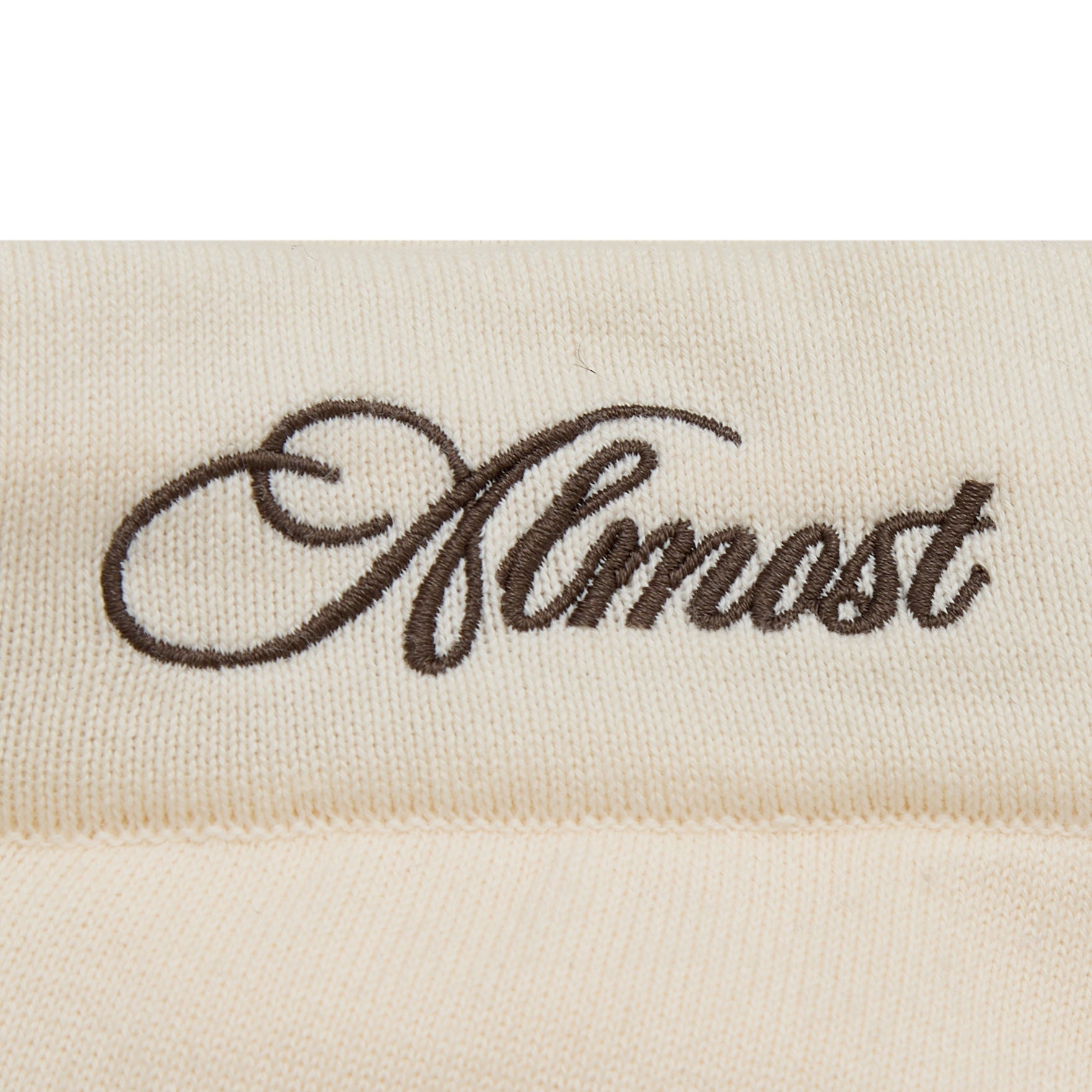 Embroidered word 'Almost' on a beige fabric background