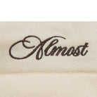 Embroidered word 'Almost' on a beige fabric background