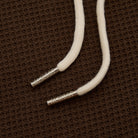 White cord with metal ends on a brown textured background
