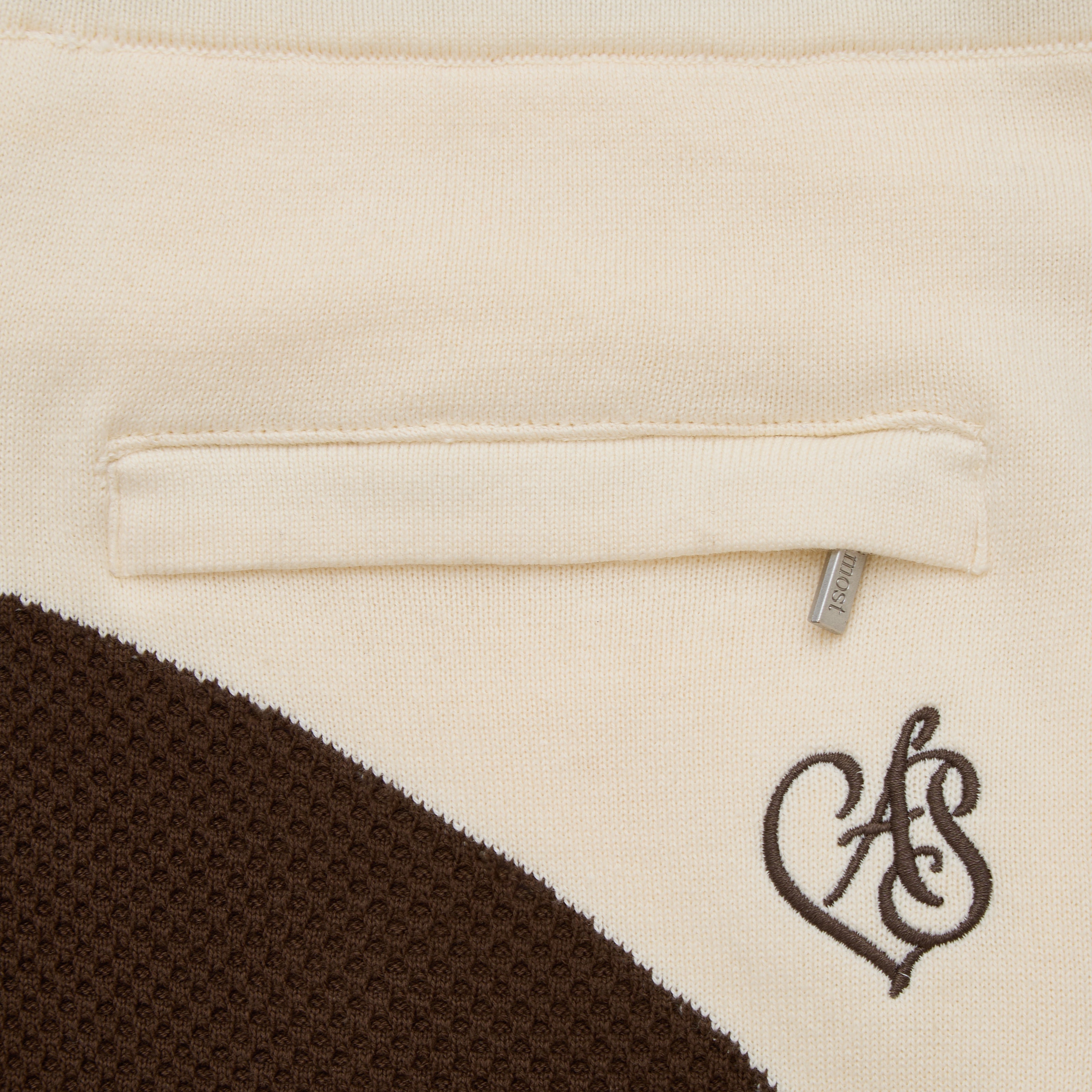 Close-up of a beige fabric with a brown heart-shaped logo on a label.