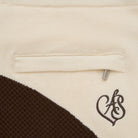 Close-up of a beige fabric with a brown heart-shaped logo on a label.