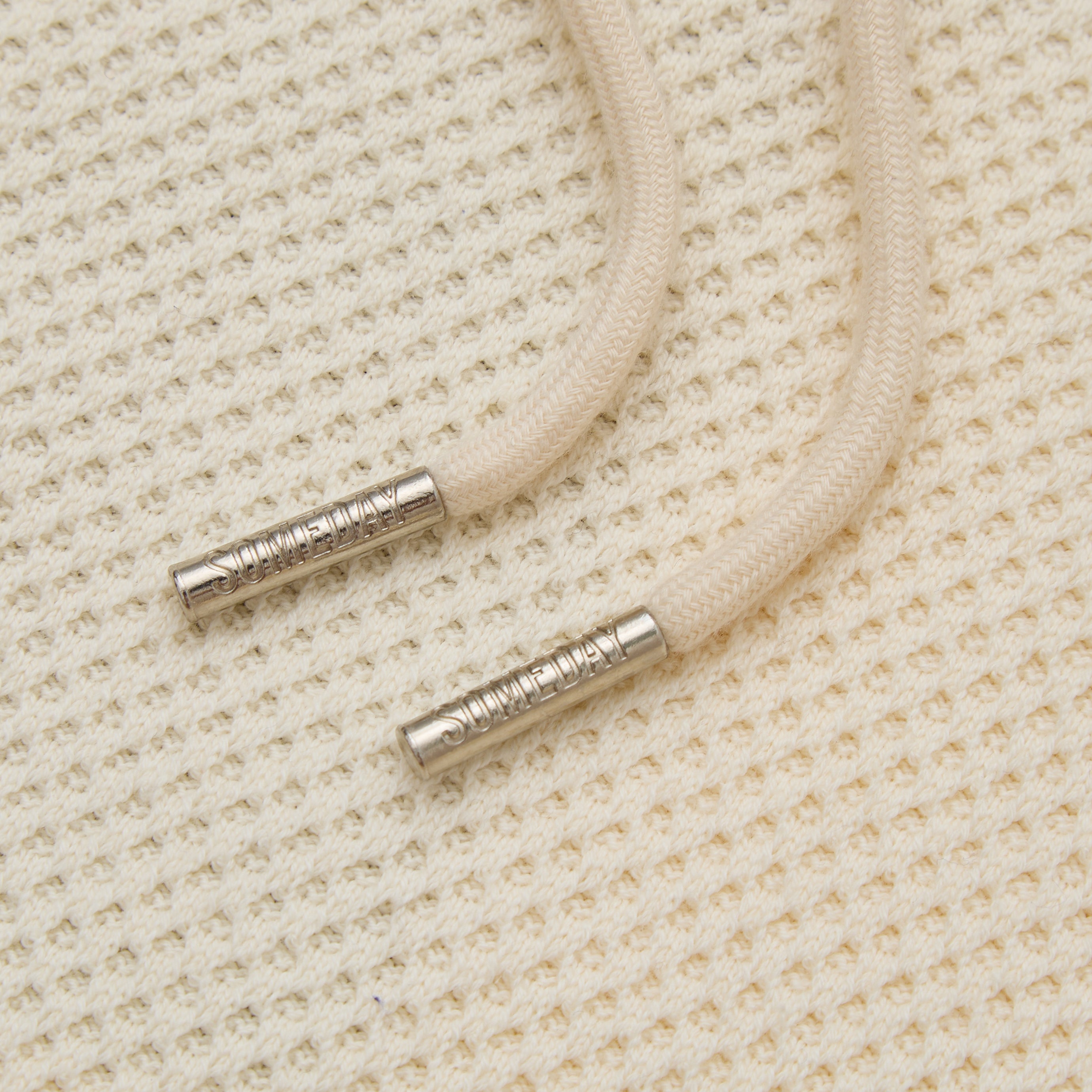 Close-up of beige cord with metal ends on a textured beige background