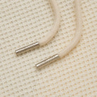 Close-up of beige cord with metal ends on a textured beige background