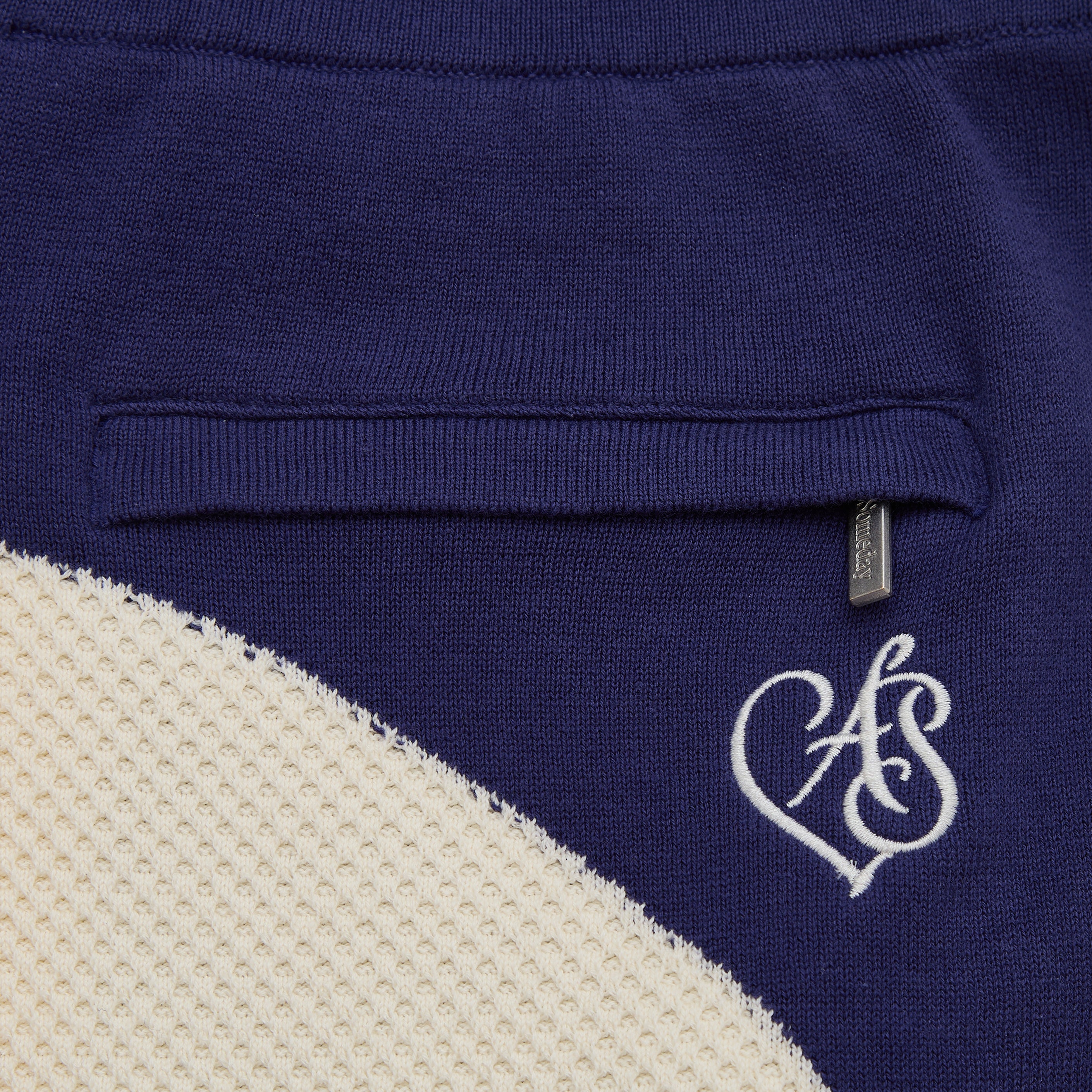 Close-up of a blue garment with a white logo on a beige background
