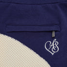 Close-up of a blue garment with a white logo on a beige background