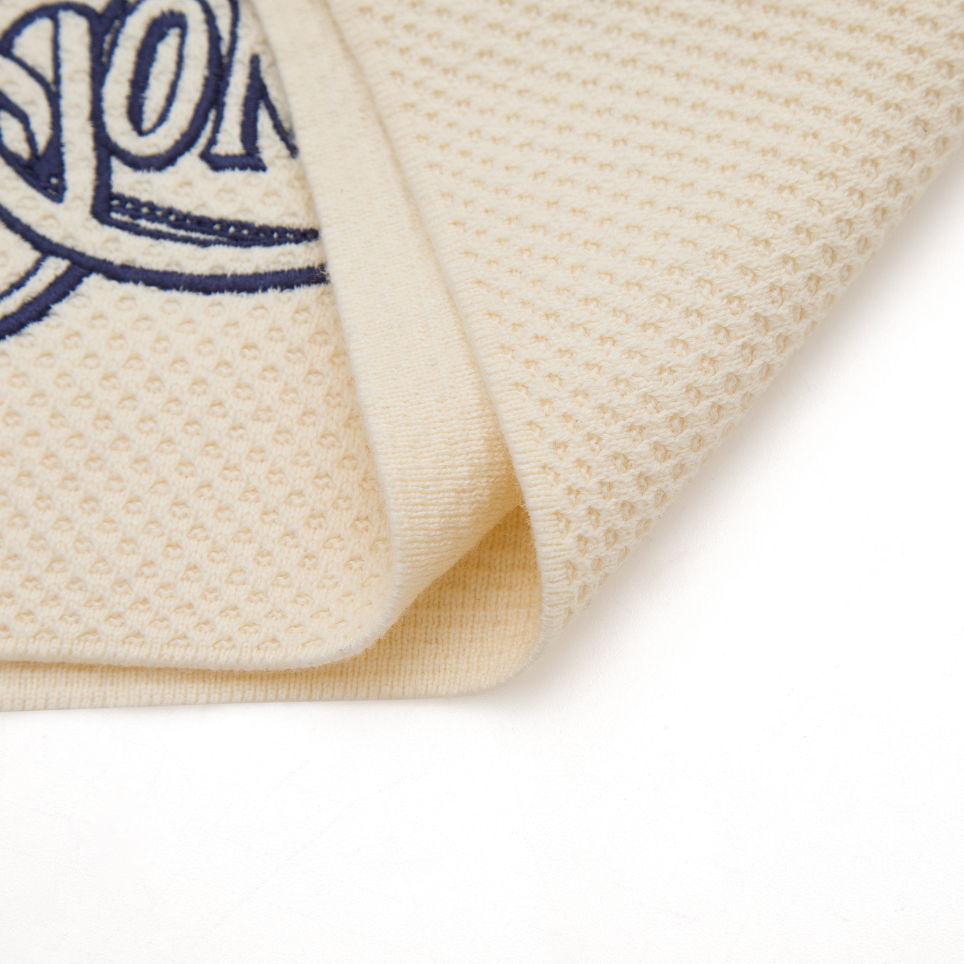 Close-up of a textured beige fabric with a blue logo on a white background