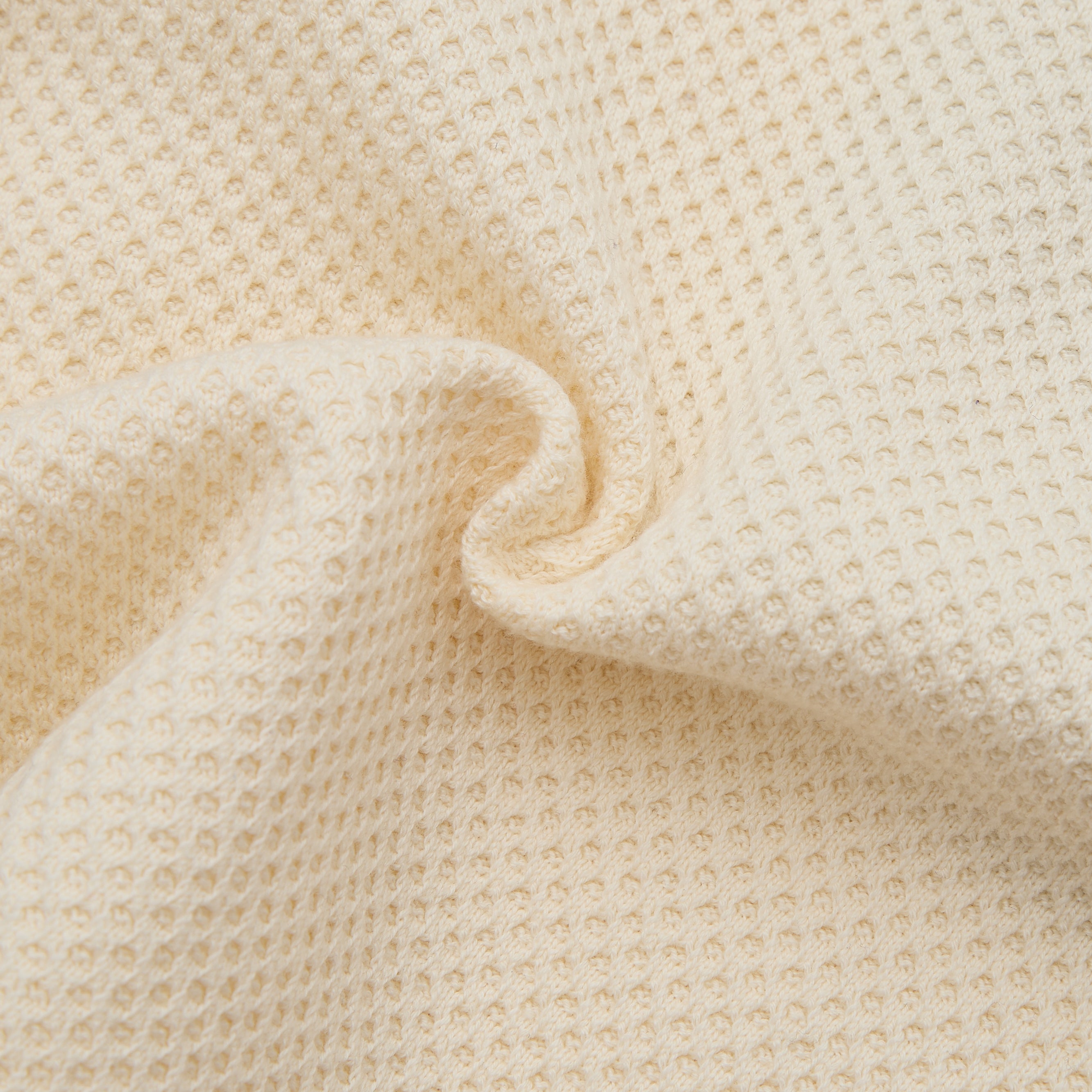 Close-up of beige textured fabric with a slight waffle pattern.