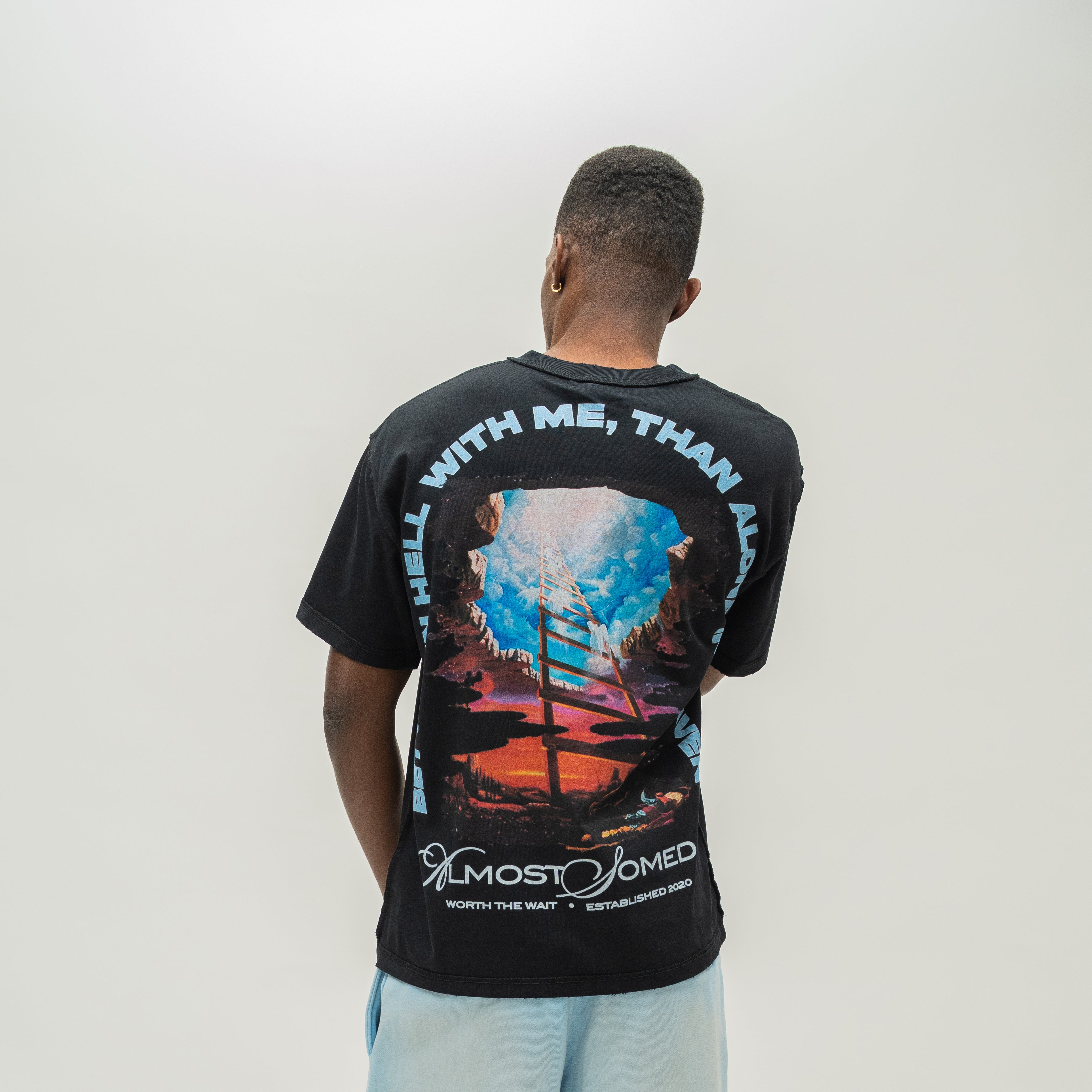 A man viewed from behind wearing a black t-shirt with a large colorful graphic print on the back.