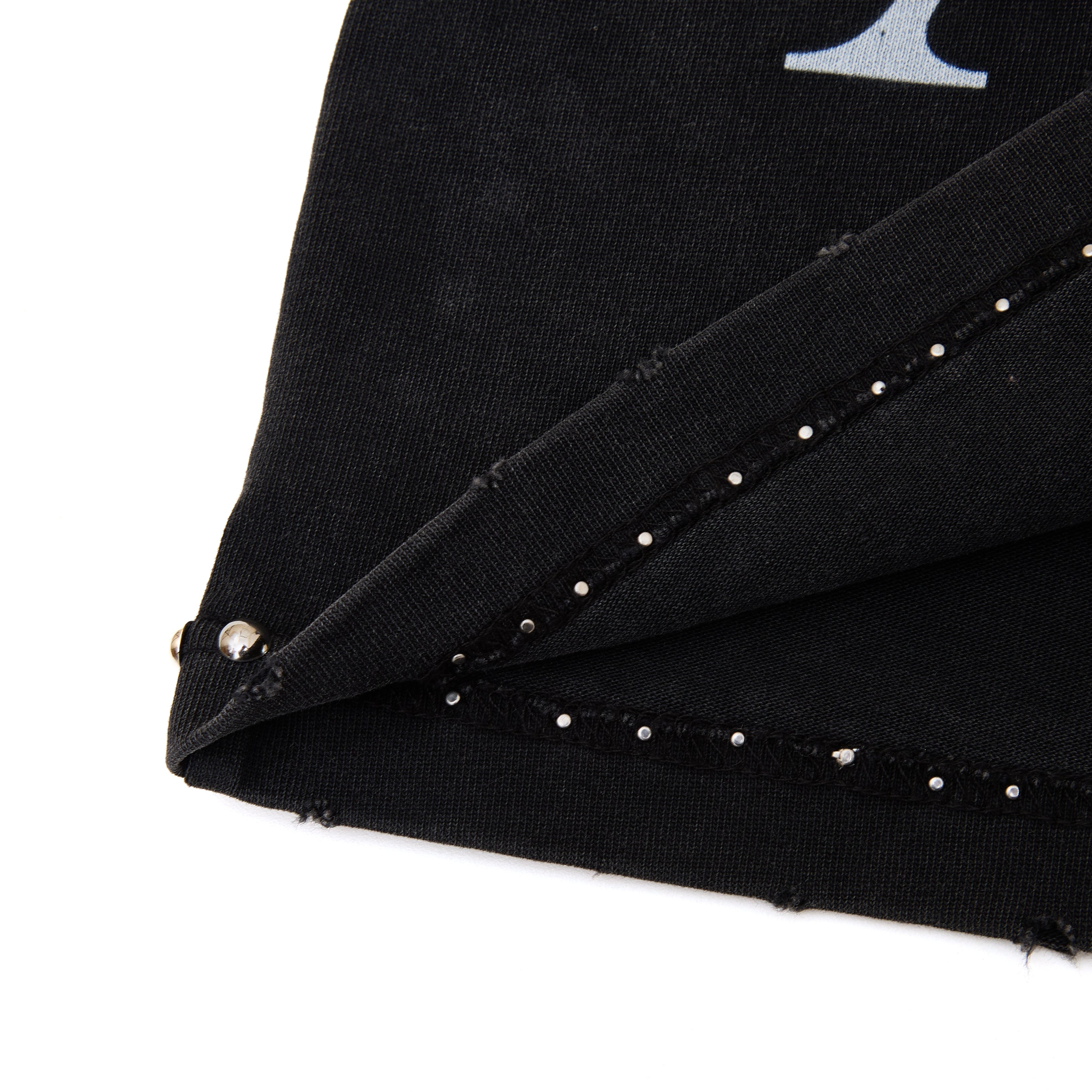 Close-up of a black fabric with silver studs on a white background