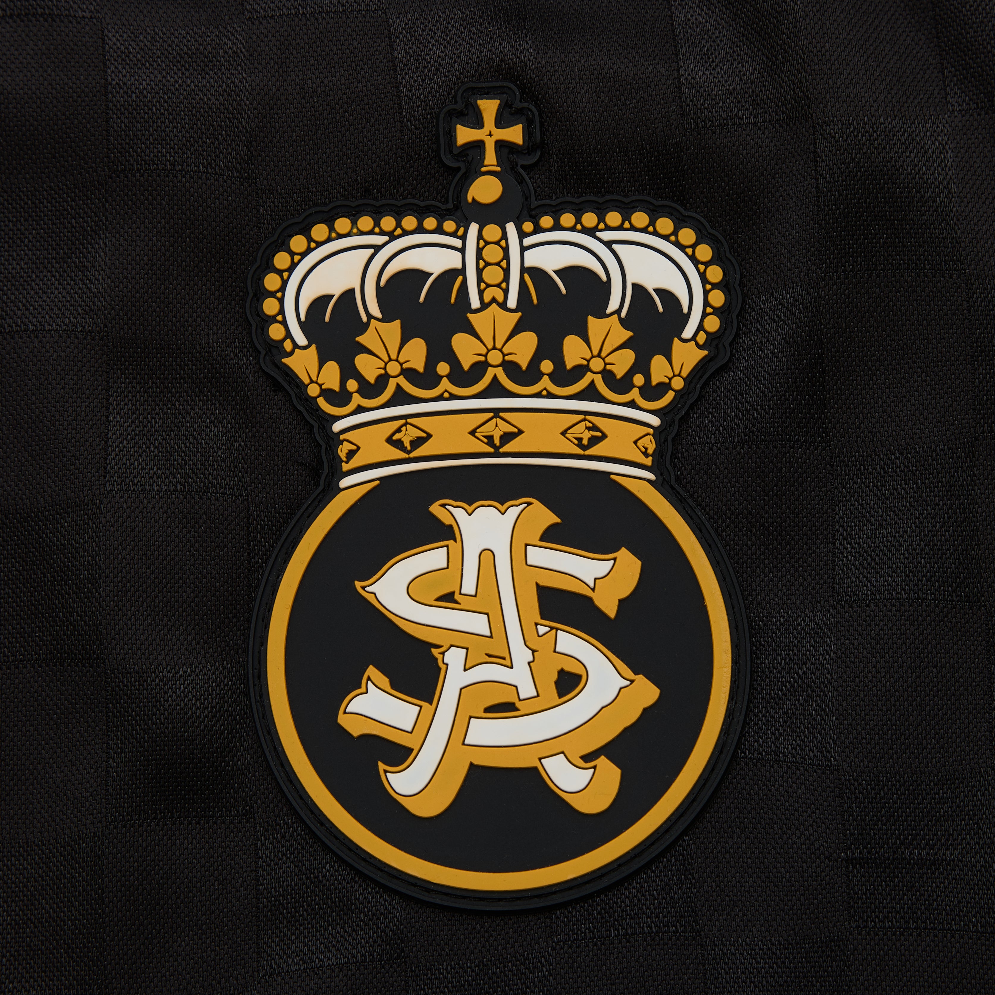 Embroidered logo with a crown and initials on a black background