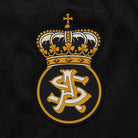 Embroidered logo with a crown and initials on a black background